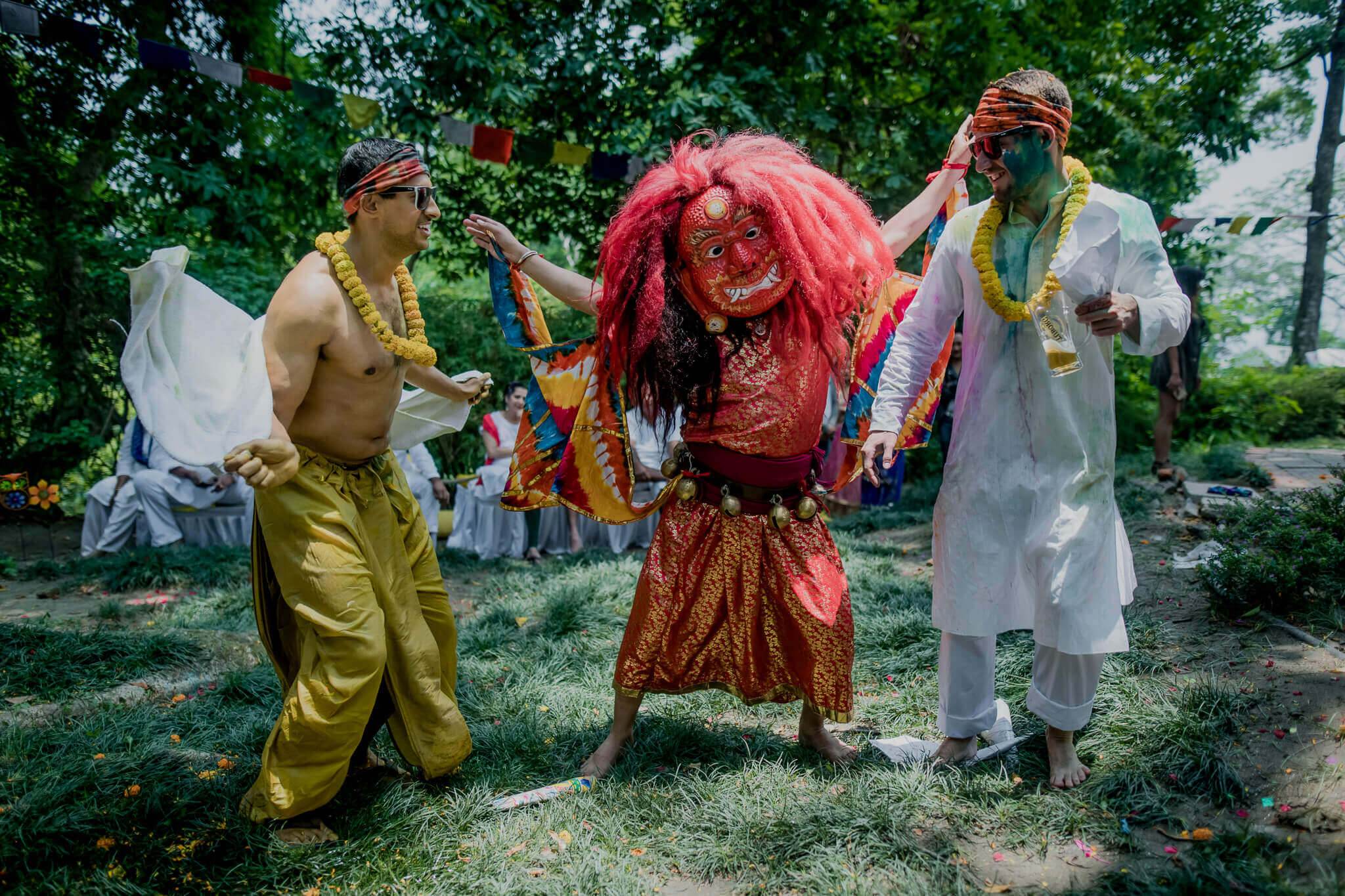 Anu and Raghu celebrate with friends in vibrant traditional Nepali attire in a lush garden setting