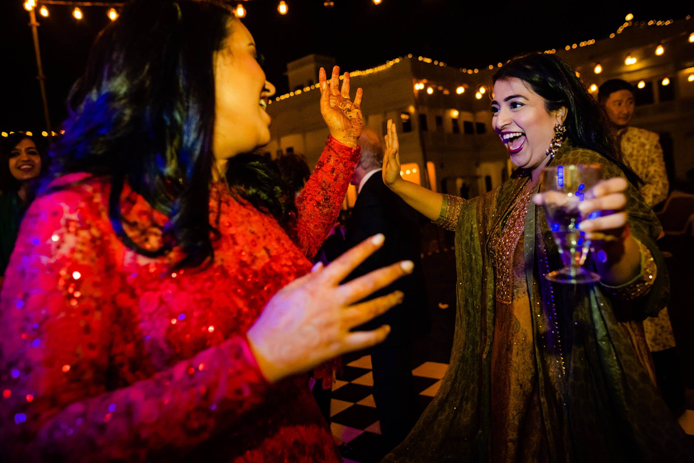 Maitrayee and Eric celebrate with guests in festive attire under warm string lights in Rajasthan
