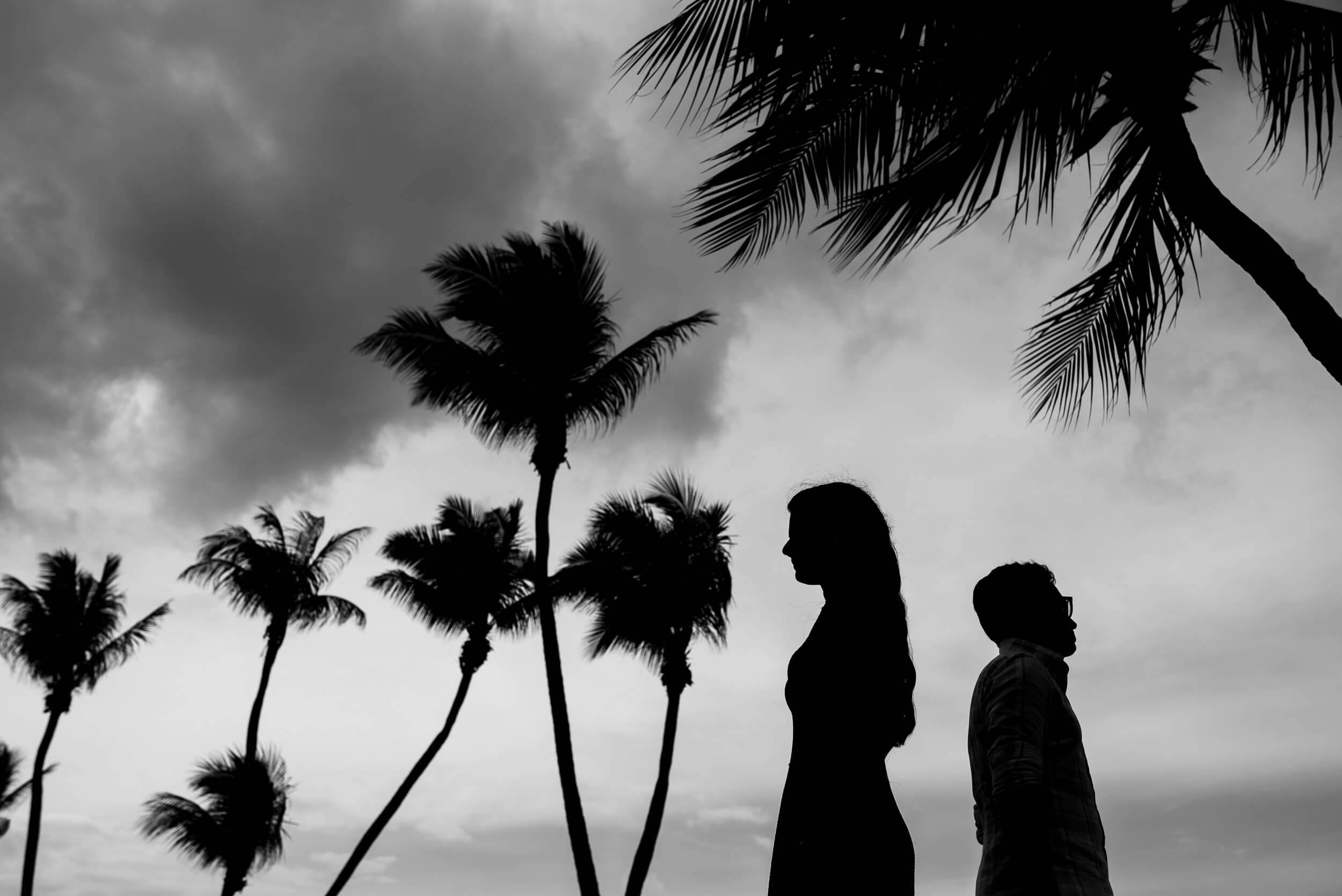 Yash and Disha silhouetted against dramatic sky with palm trees, Singapore