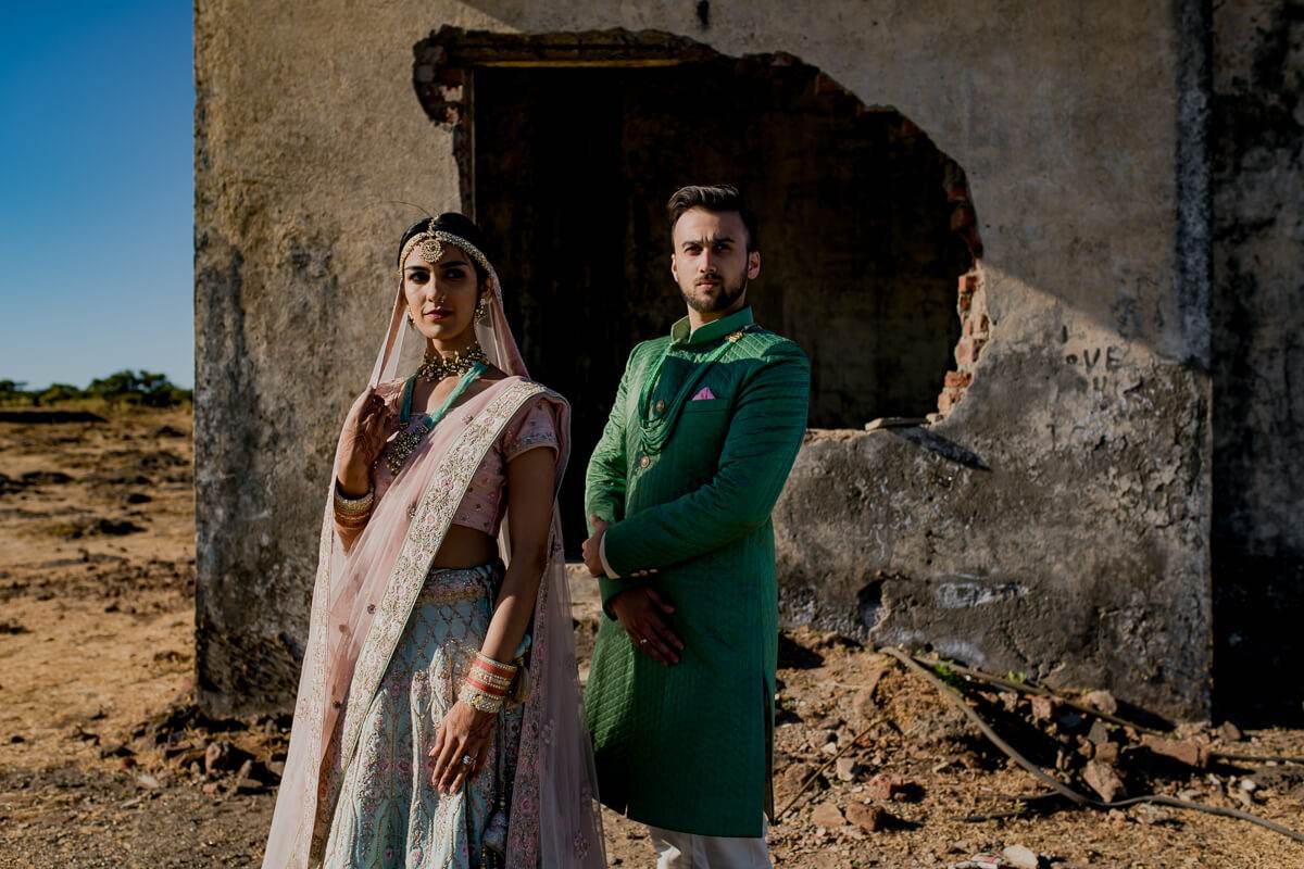 Shreya and Yash stand at a weathered stone doorway in Mahabaleshwar, wearing traditional attire