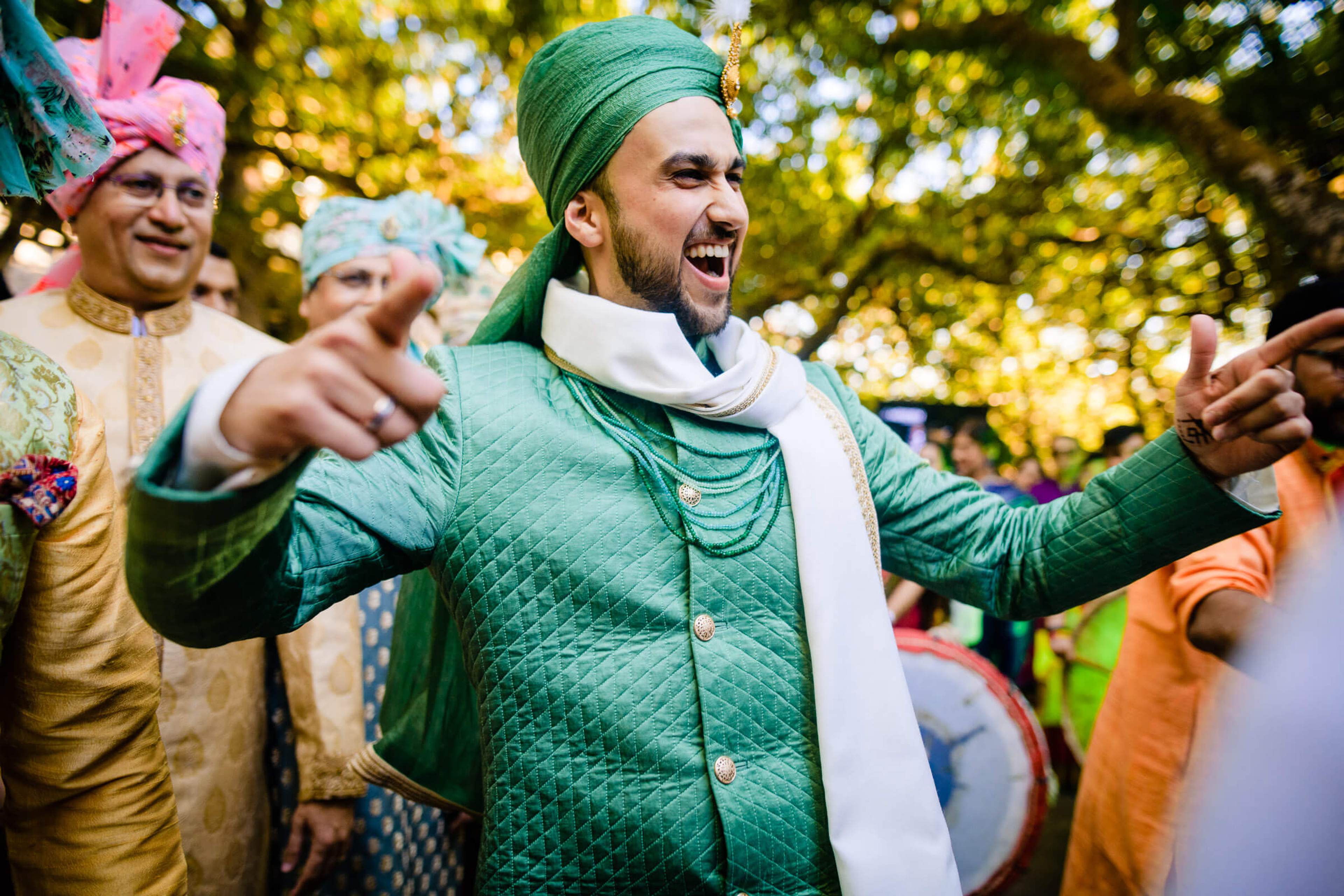 Groom Yash smiling with arms outstretched in green traditional attire at Mahabaleshwar celebration