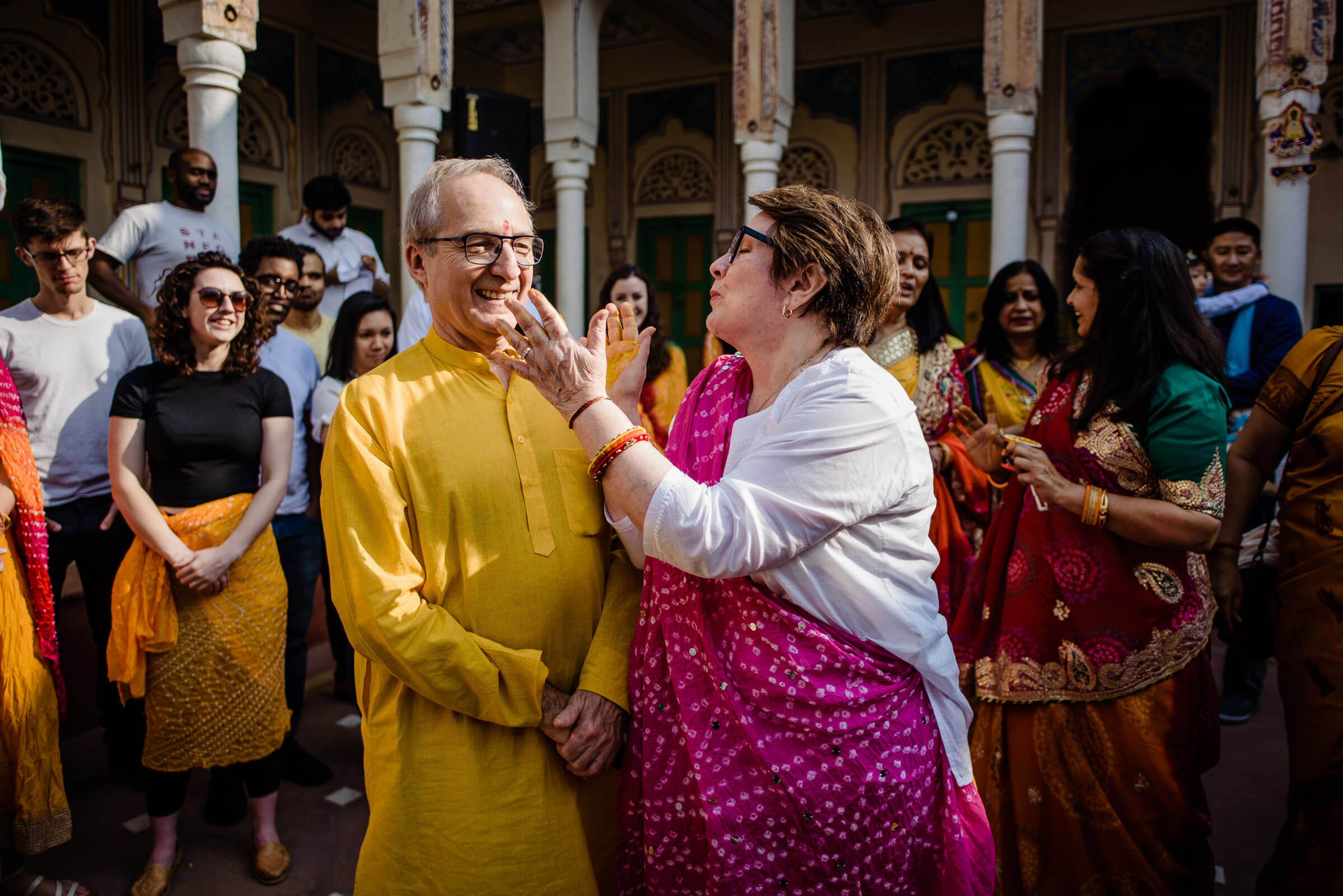 Maitrayee and Eric celebrate with family in traditional attire within ornate Rajasthan temple courtyard