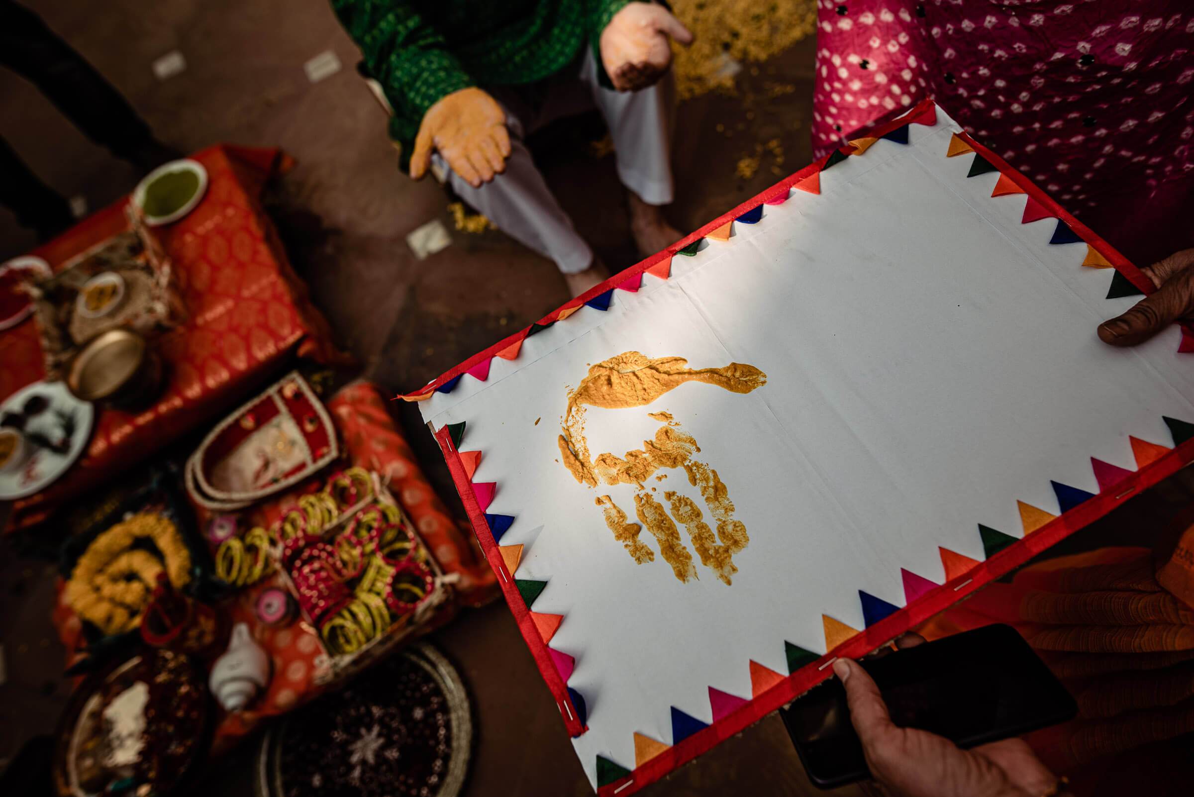Maitrayee and Eric's henna application in Rajasthan, showing golden paste handprint on white cloth with red border
