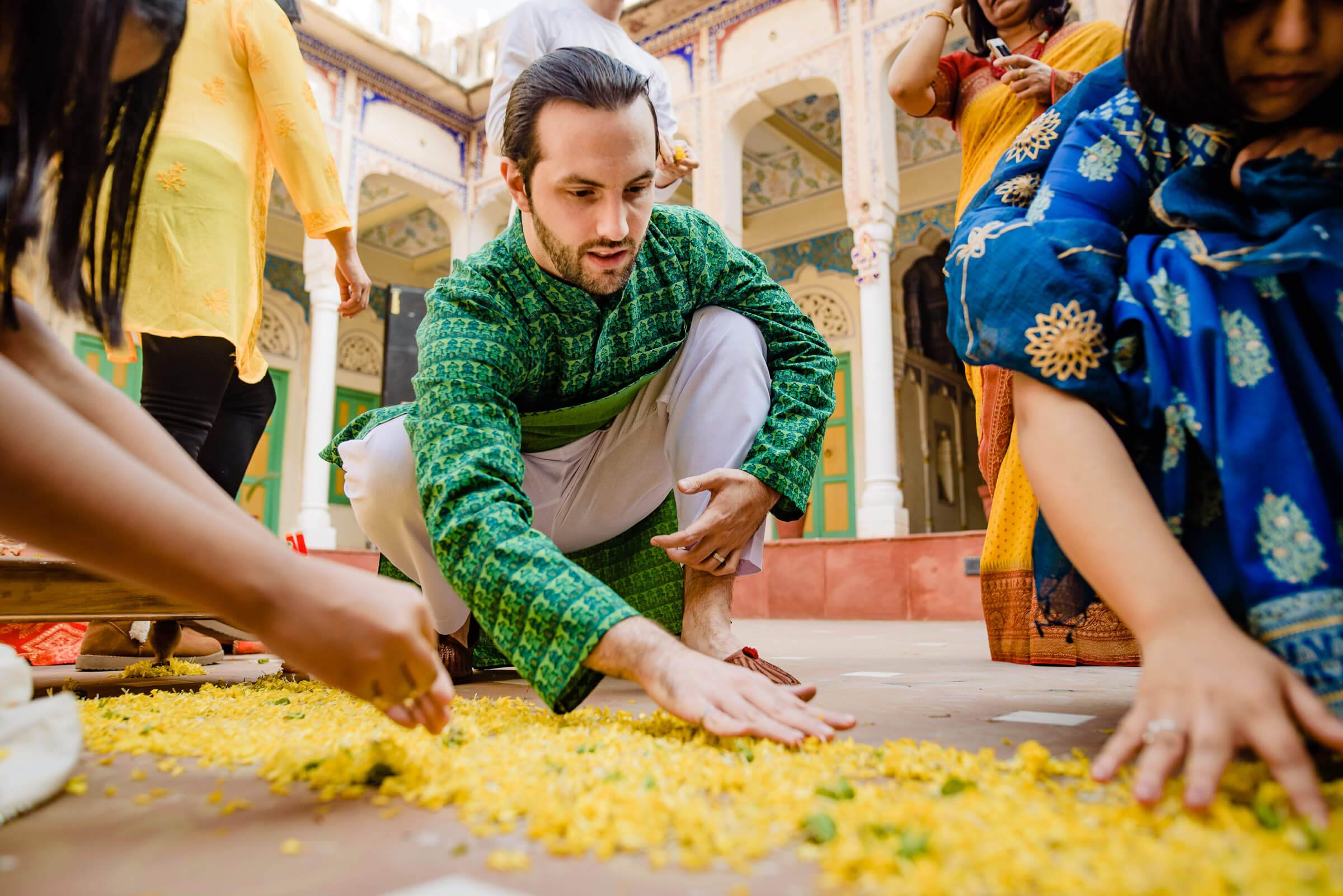 Maitrayee and Eric spread yellow petals in a Rajasthan courtyard surrounded by colorful guests