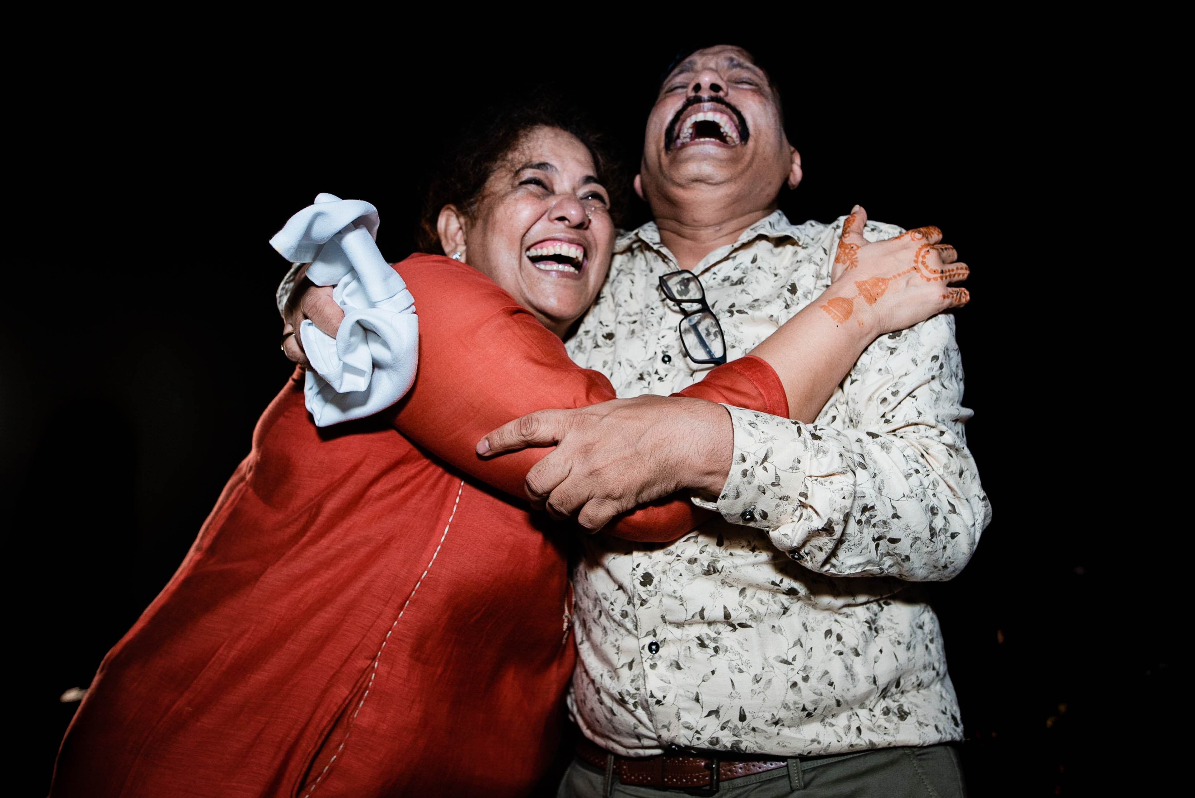 Avani and Srikant laughing joyfully together against a black background in Goa