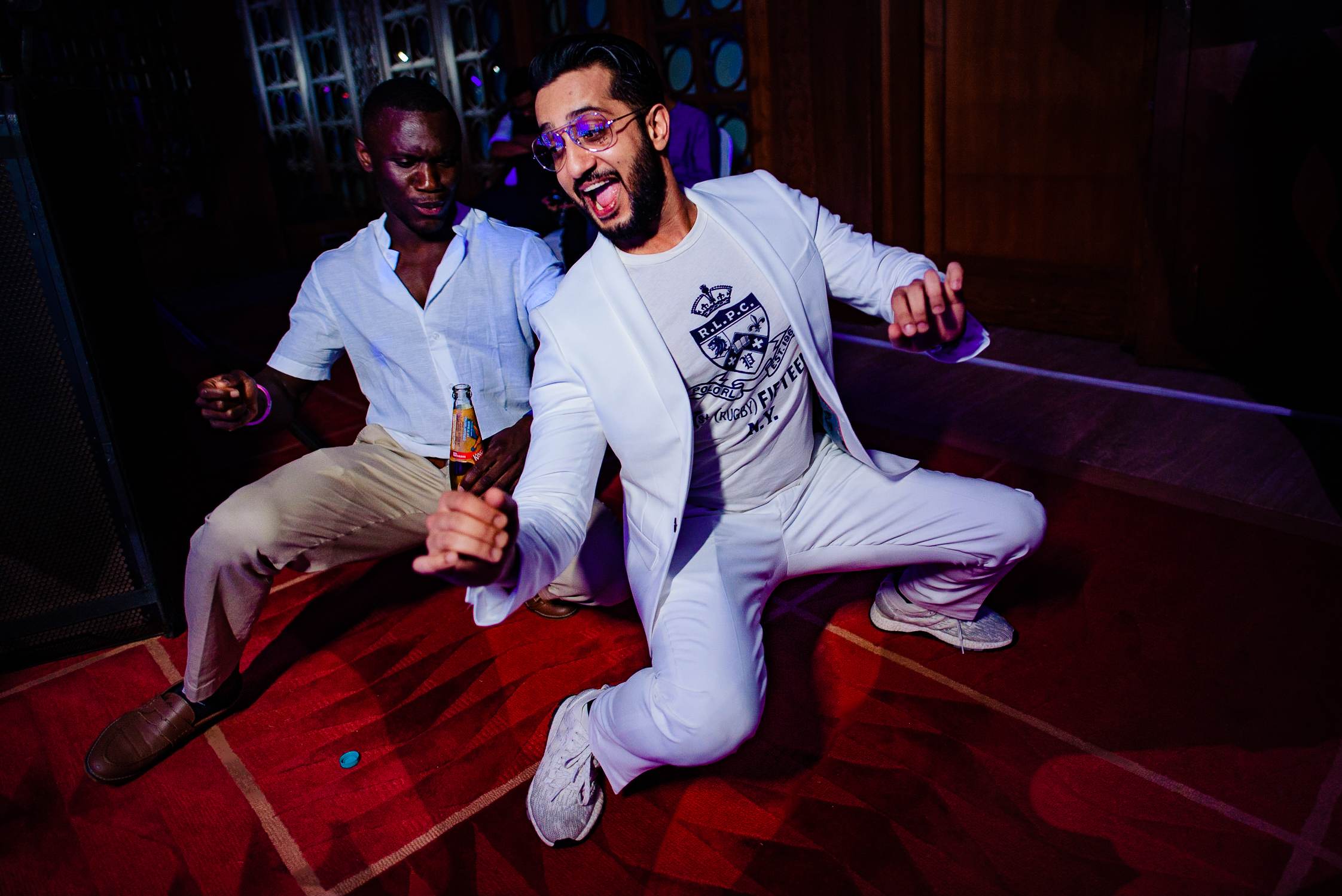 Avani and Srikant celebrate at a Goa nightclub in white outfits, dancing under purple lighting on red floor