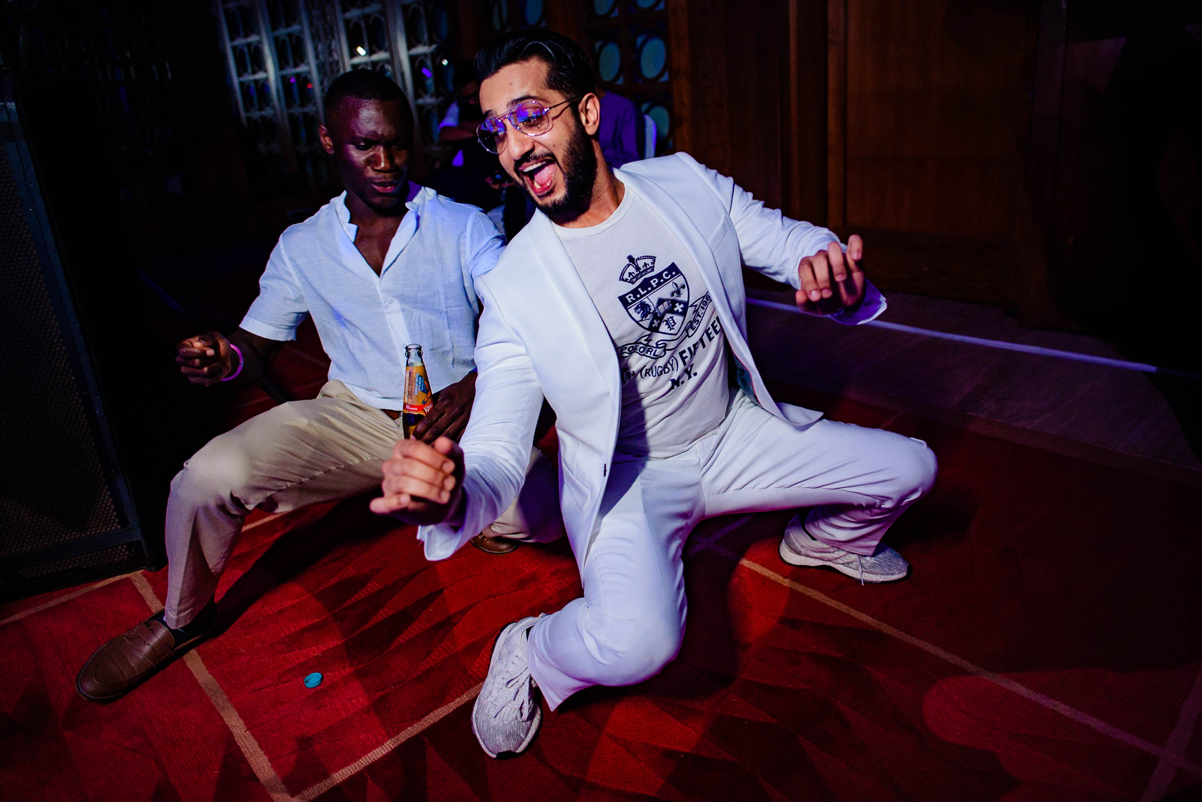 Avani and Srikant celebrate at a Goa nightclub in white outfits, dancing under purple lighting on red floor