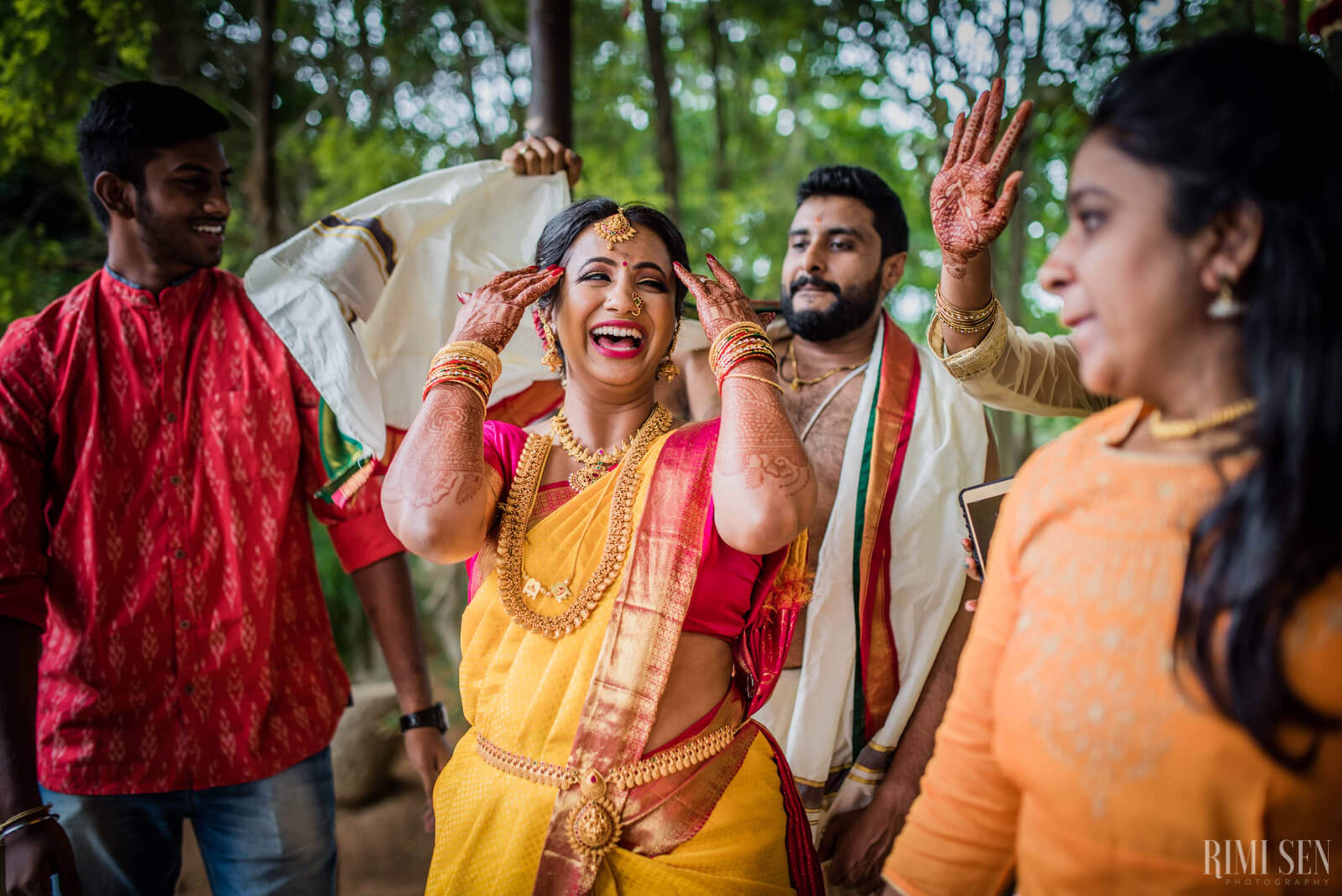 Nivetha celebrates with henna-adorned hands surrounded by family in traditional Indian wedding attire outdoors