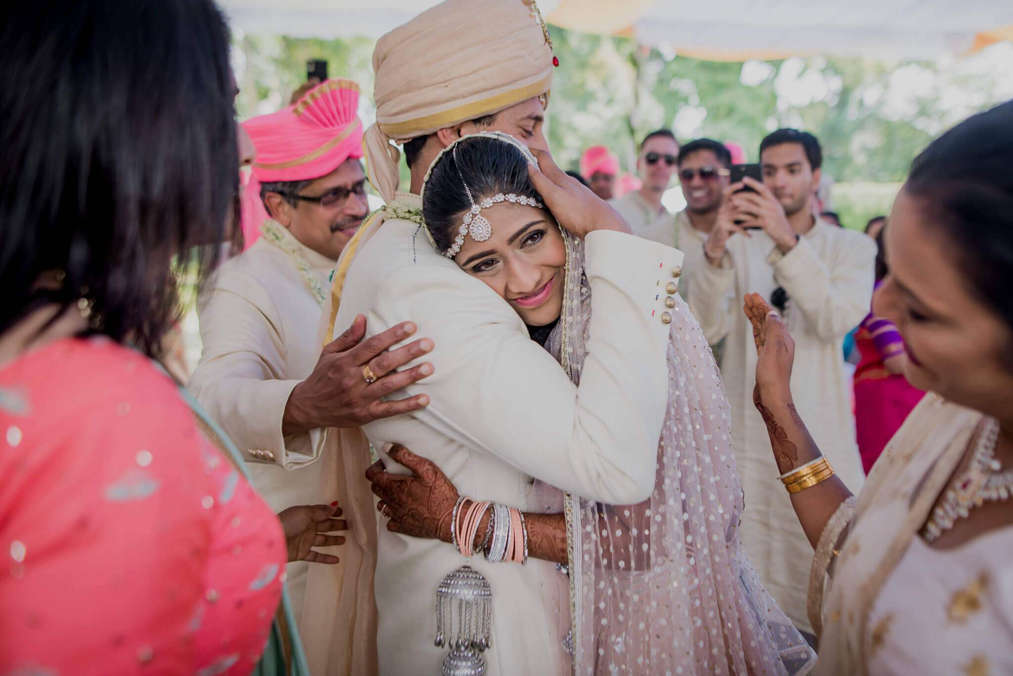Anu and Raghu embrace during a traditional Nepali wedding celebration surrounded by guests in festive attire