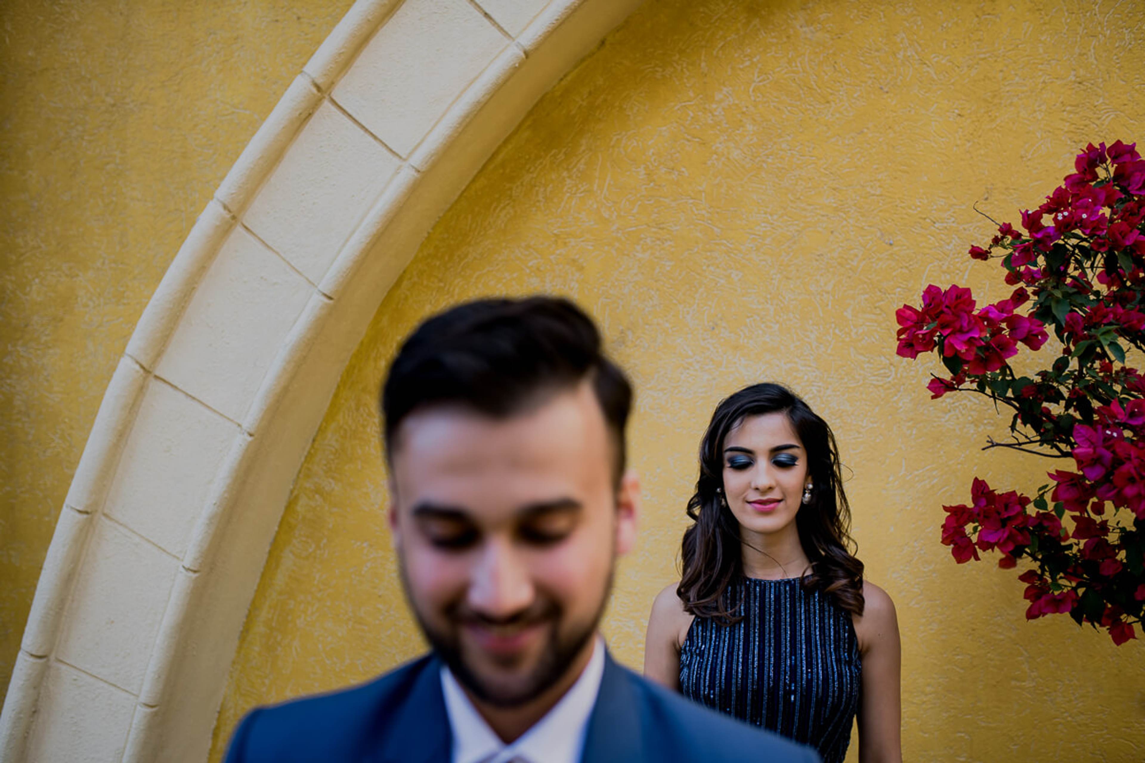 Shreya and Yash stand before a golden arch with magenta bougainvillea at Mahabaleshwar