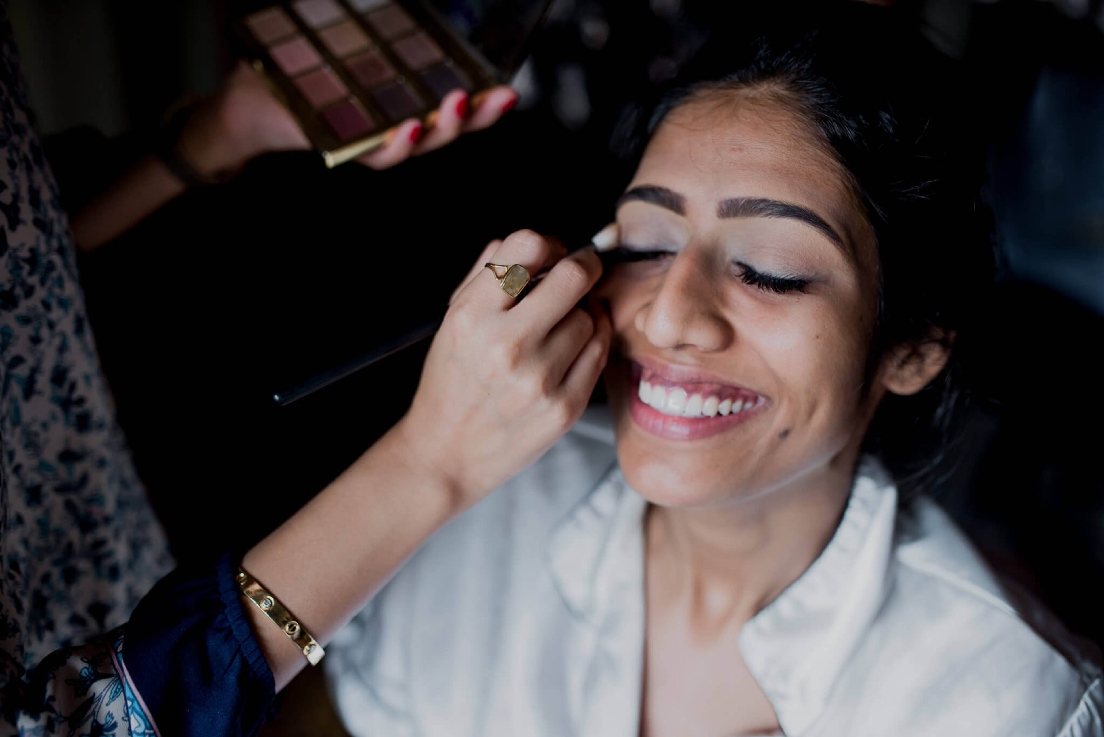 Anu smiles as a makeup artist applies eyeliner before her wedding day in Nepal