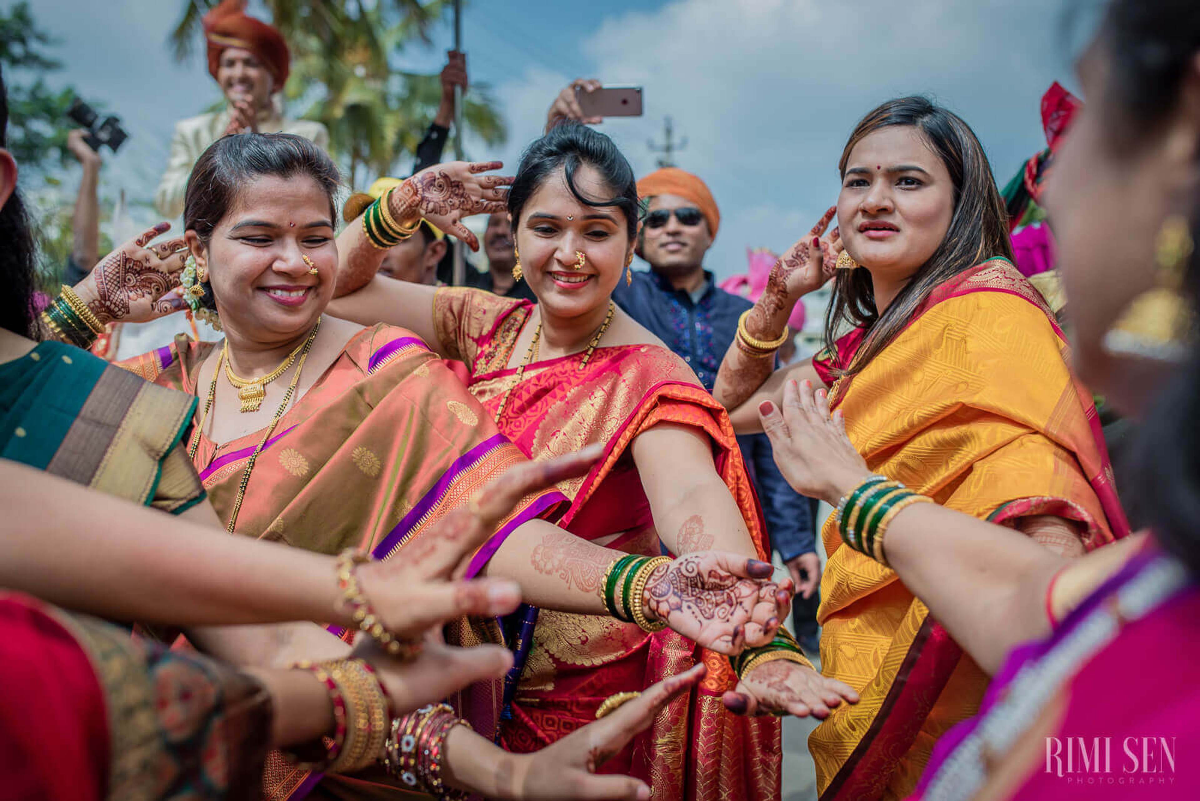 Women in colorful traditional Indian attire stacked hands together, celebrating outdoors in Bangalore