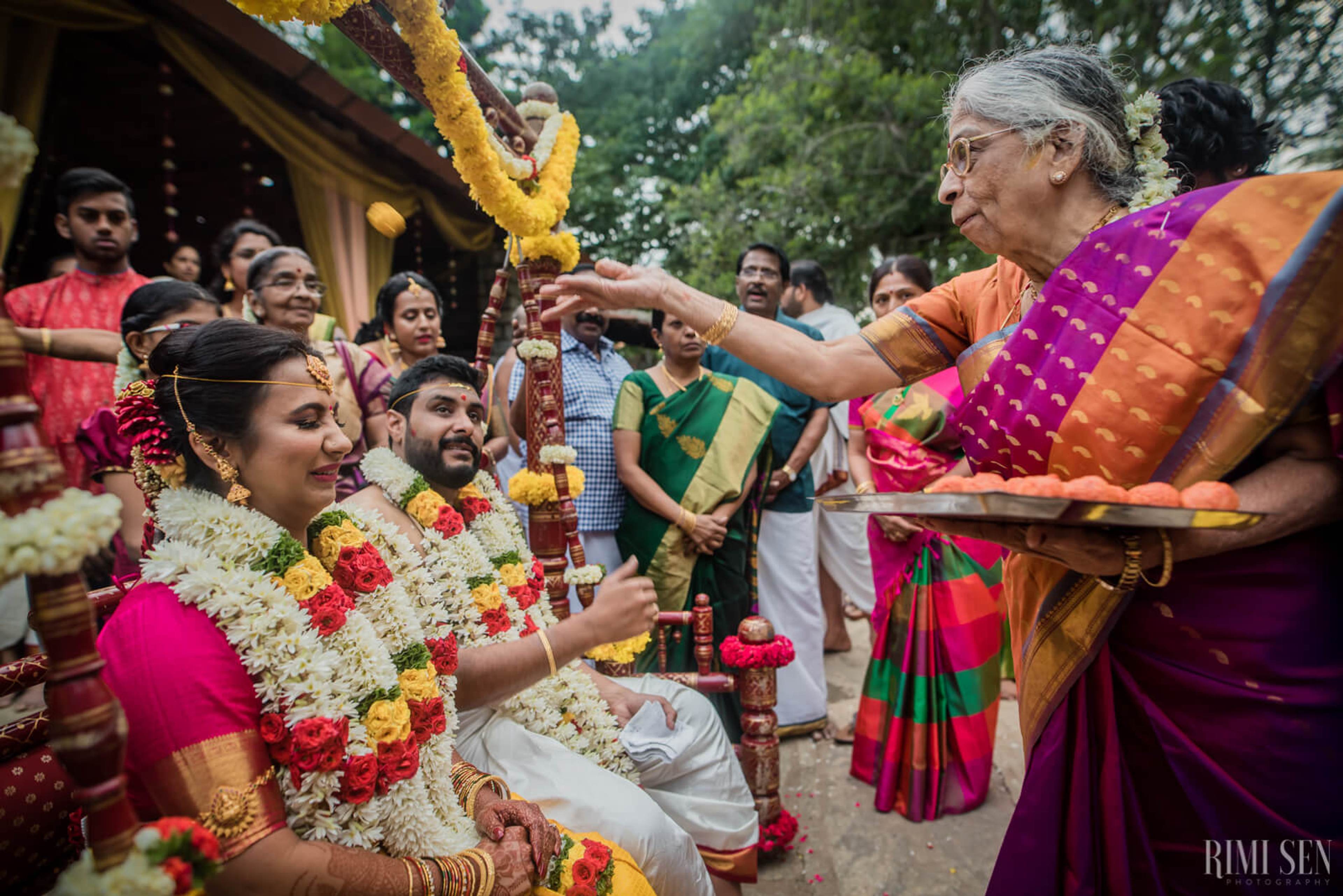 Nivetha and Sridhar receive blessings during their wedding ceremony in Bangalore, surrounded by family in traditional attire