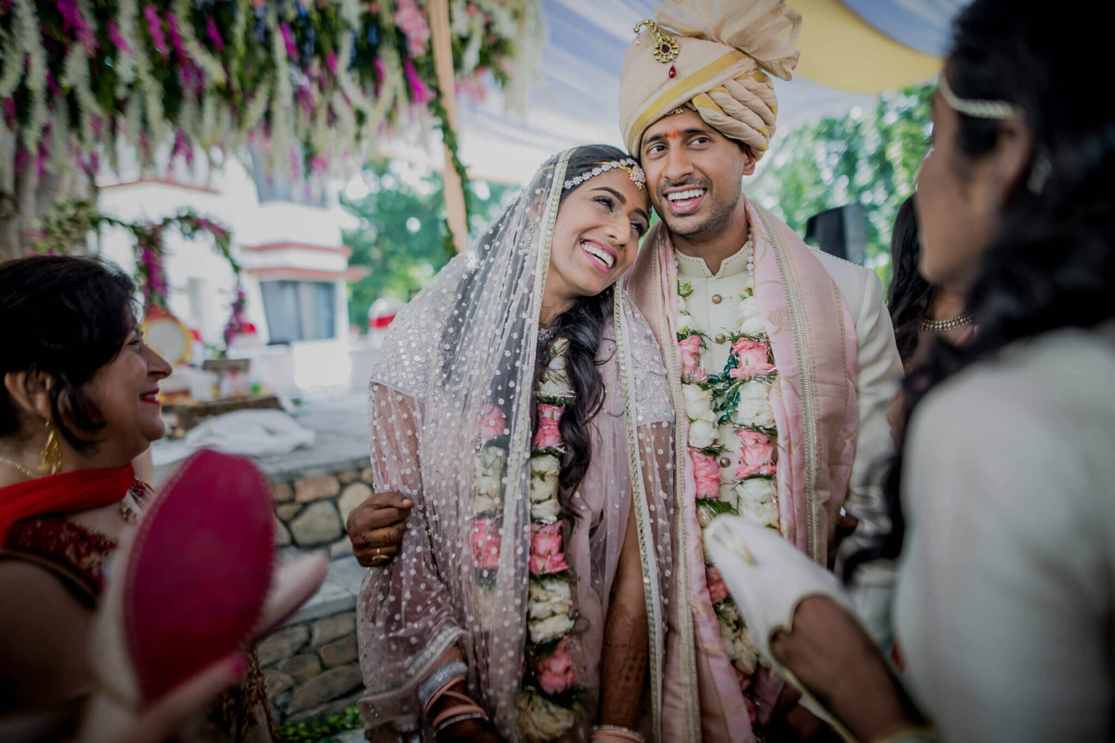 Anu and Raghu smile in traditional wedding attire with flower garlands in Nepal