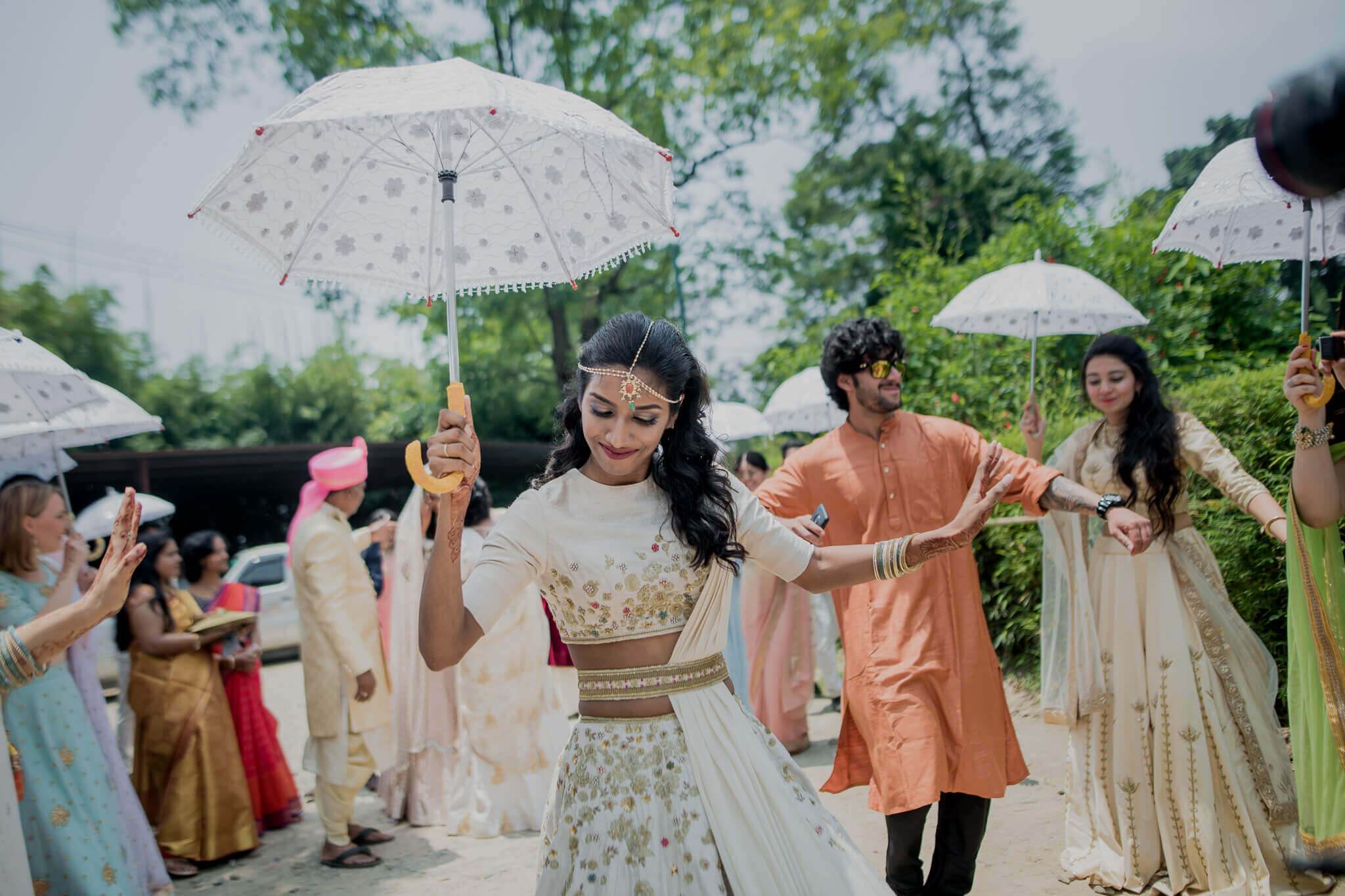 Anu and Raghu celebrate with guests holding umbrellas in traditional attire at their Nepal wedding
