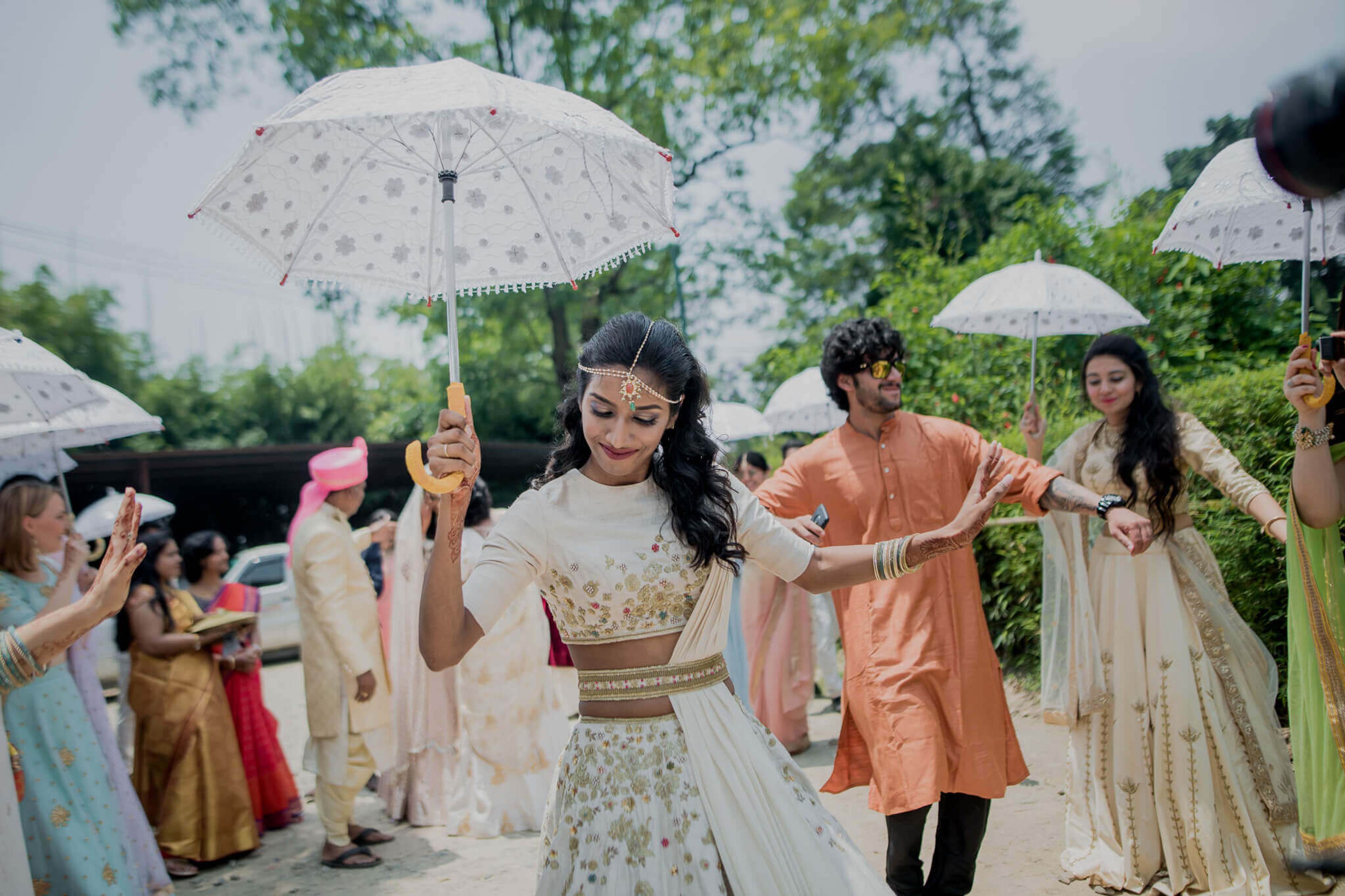 Anu and Raghu celebrate with guests holding umbrellas in traditional attire at their Nepal wedding