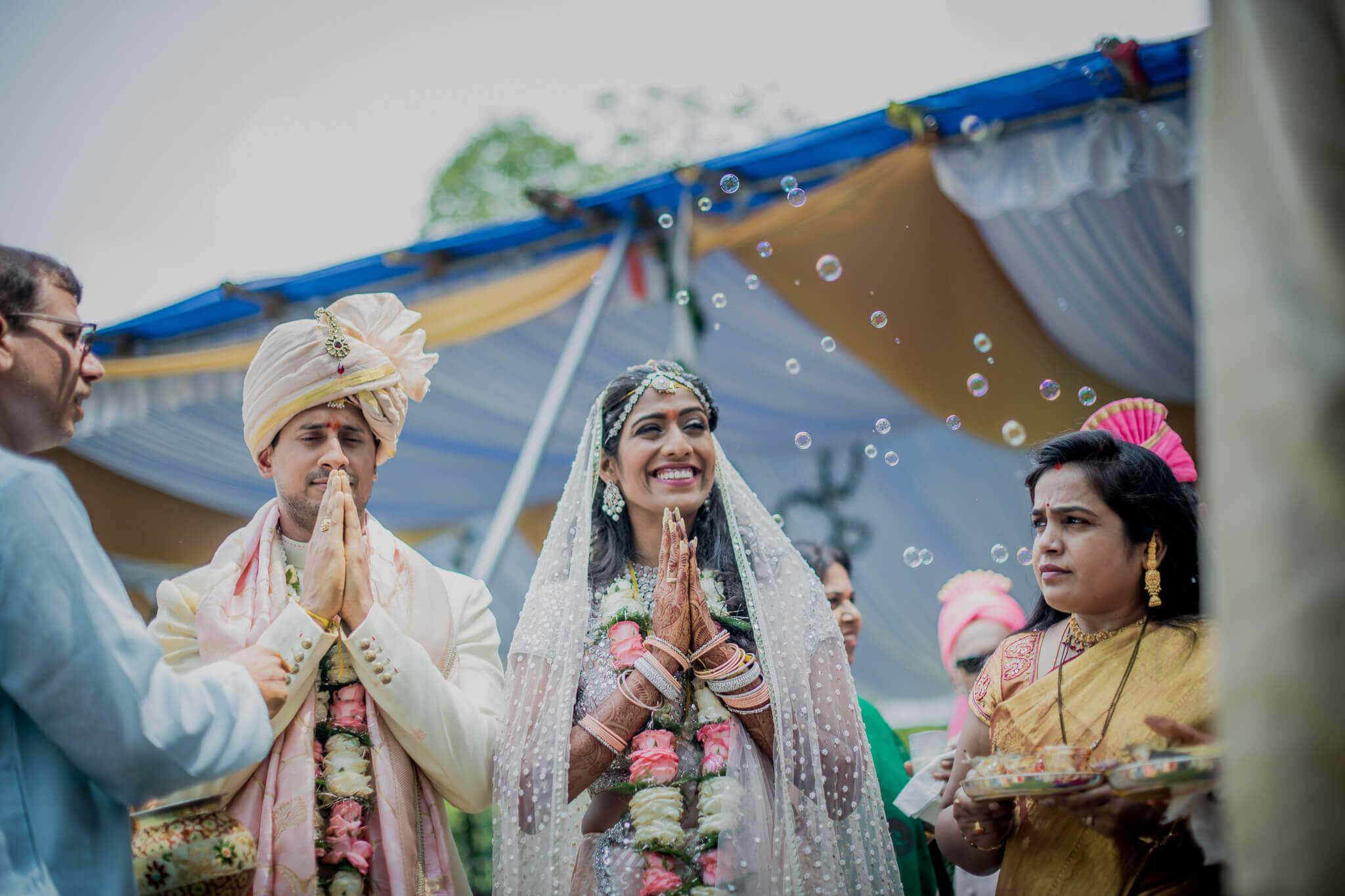 Anu and Raghu in traditional wedding attire with garlands, surrounded by family and floating bubbles at their Nepal ceremony