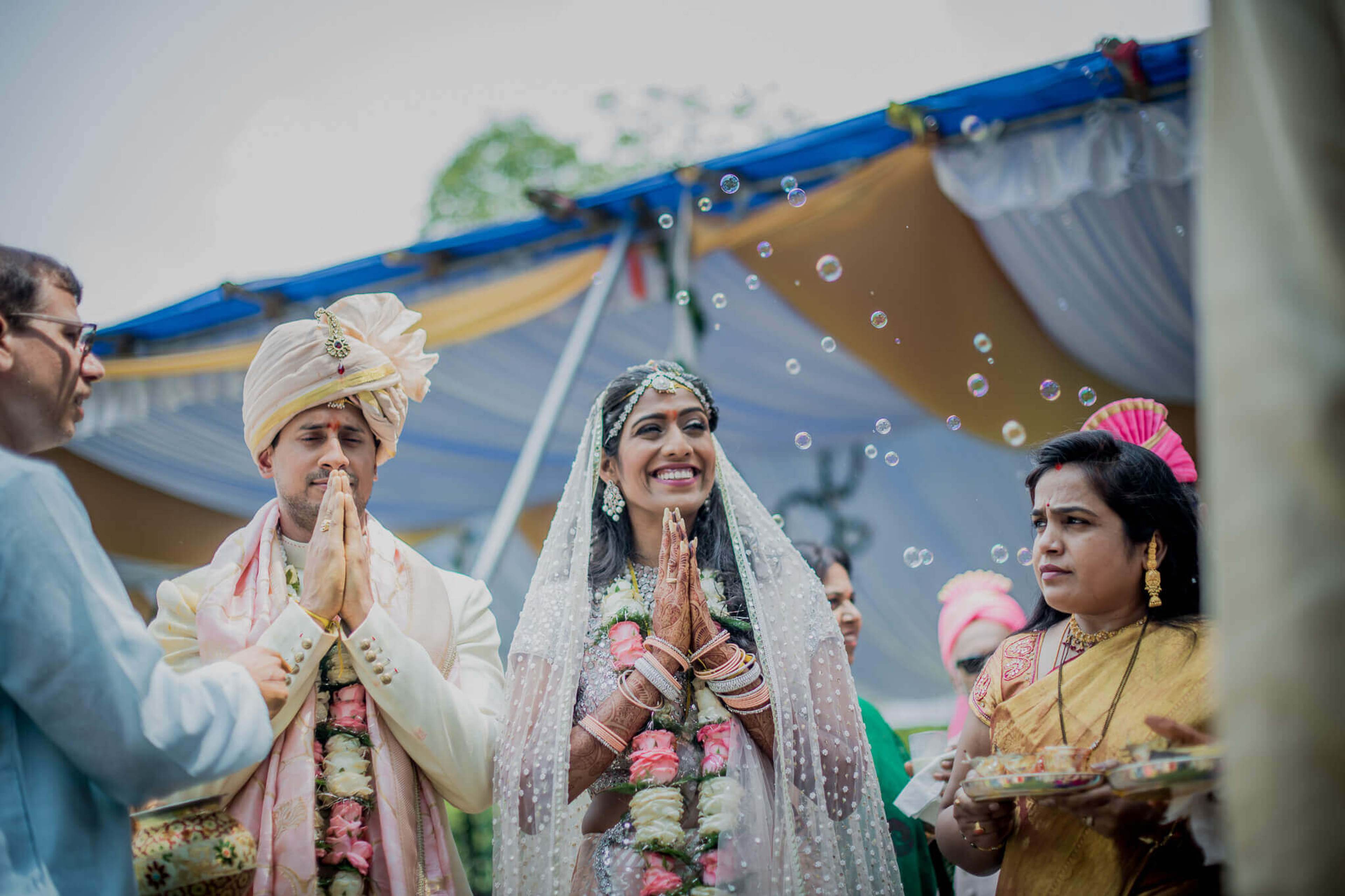 Anu and Raghu in traditional wedding attire with garlands, surrounded by family and floating bubbles at their Nepal ceremony