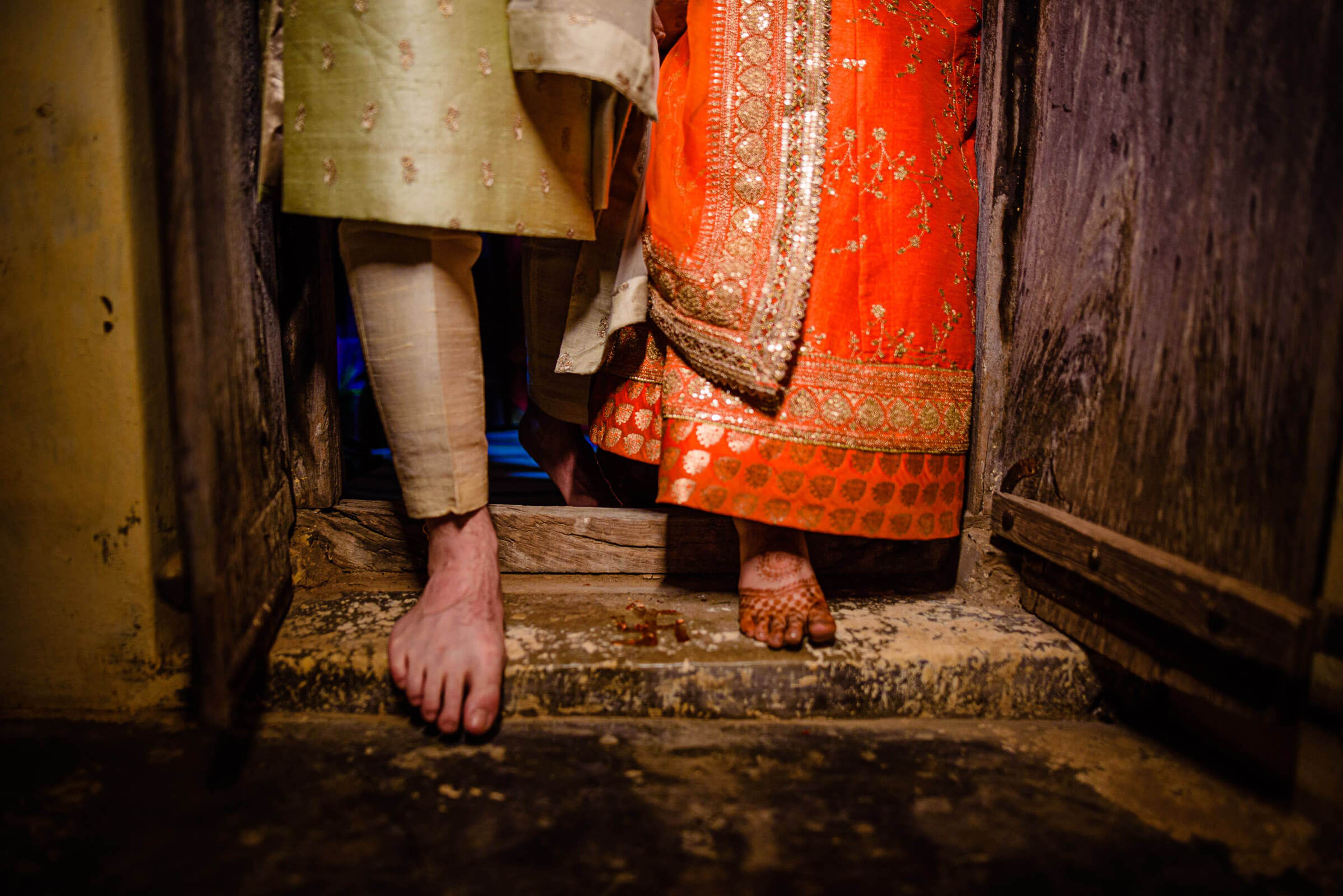 Maitrayee and Eric's bare feet on stone steps in Rajasthan, traditional orange and gold attire visible