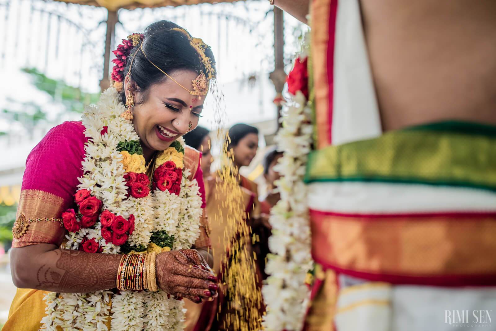 Nivetha smiles while wearing a floral garland and traditional Indian wedding attire during Bangalore ceremony