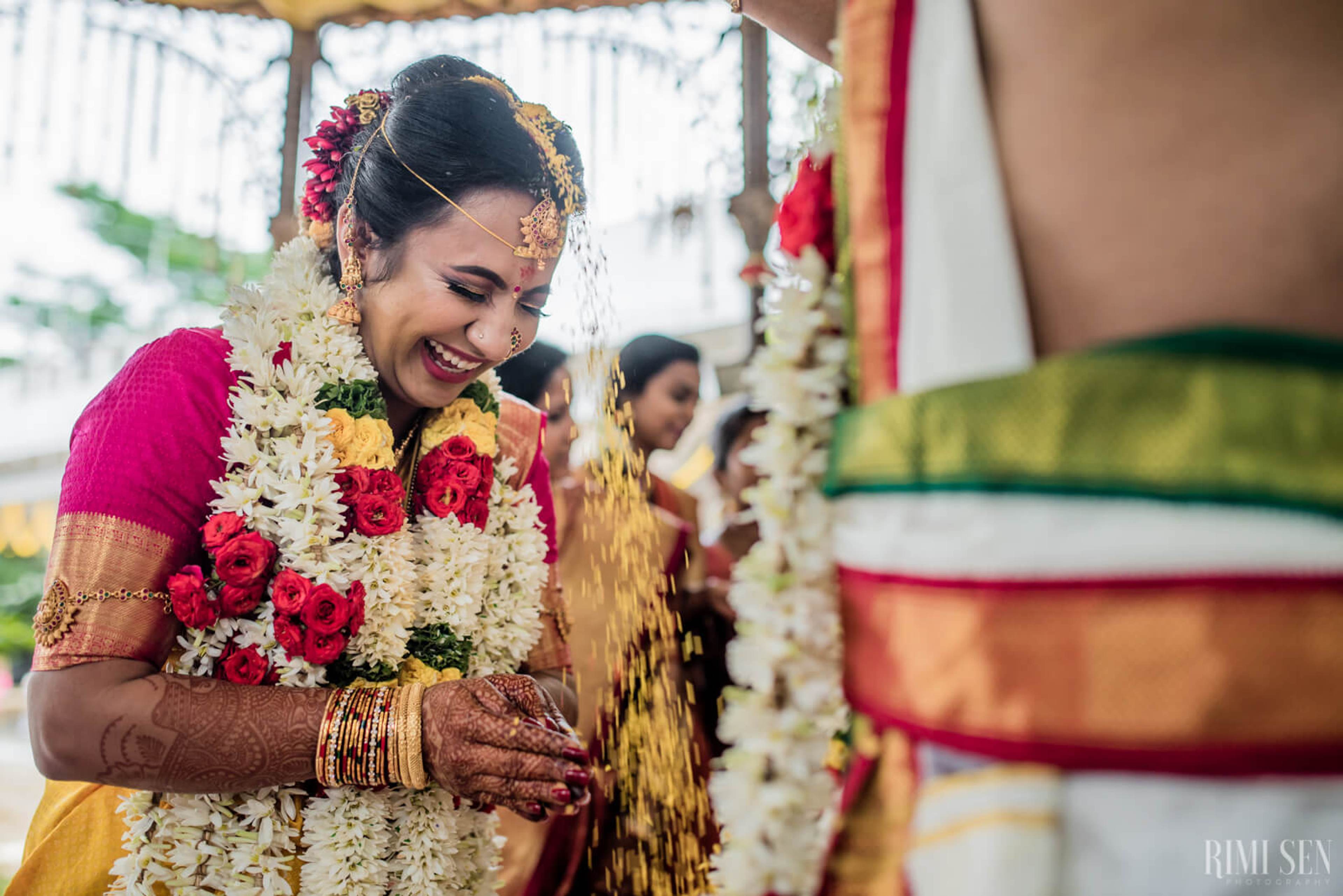 Nivetha smiles while wearing a floral garland and traditional Indian wedding attire during Bangalore ceremony