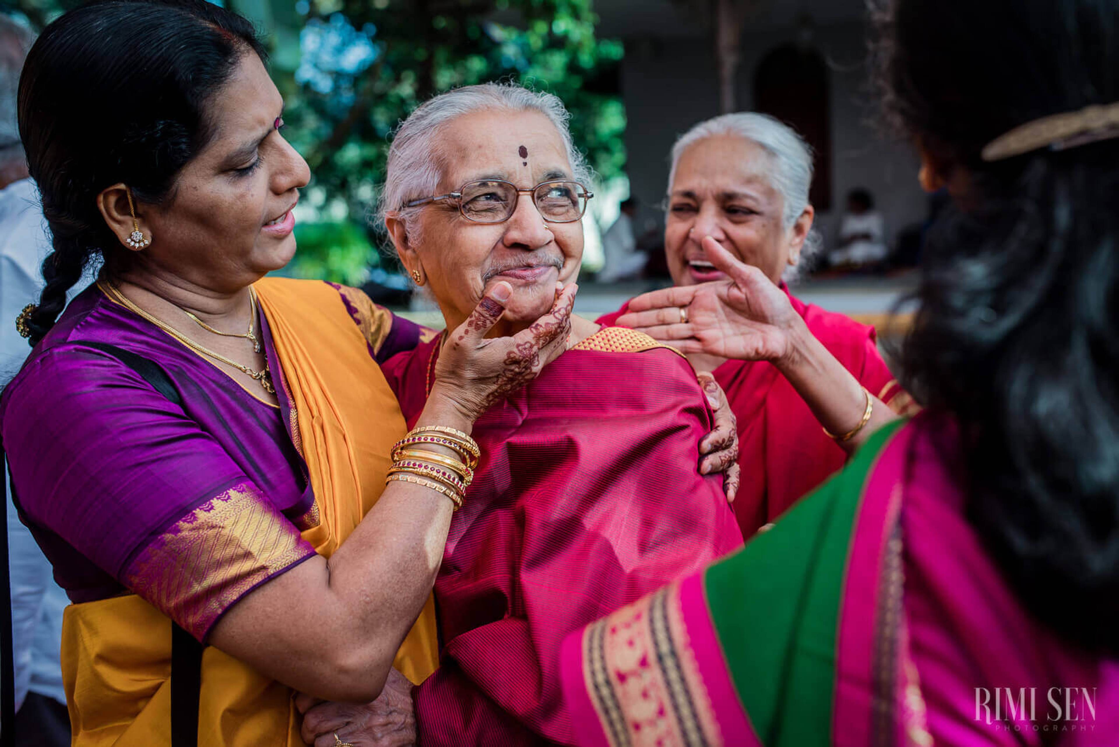 Three women in vibrant traditional attire laughing together at Bangalore wedding celebration