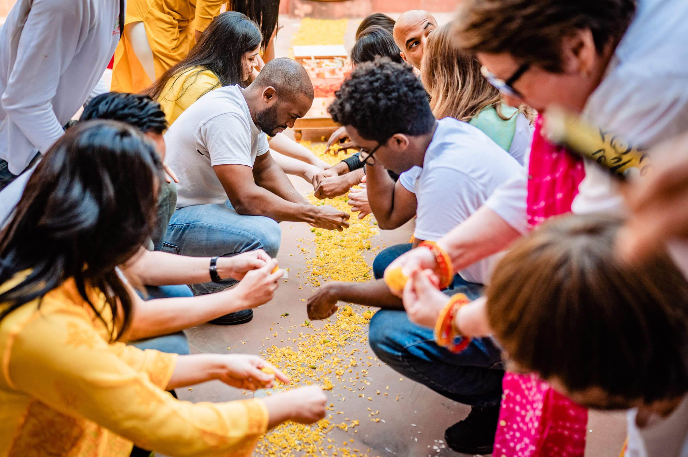 Group of guests sitting in circle playing with yellow grains during celebration in Rajasthan