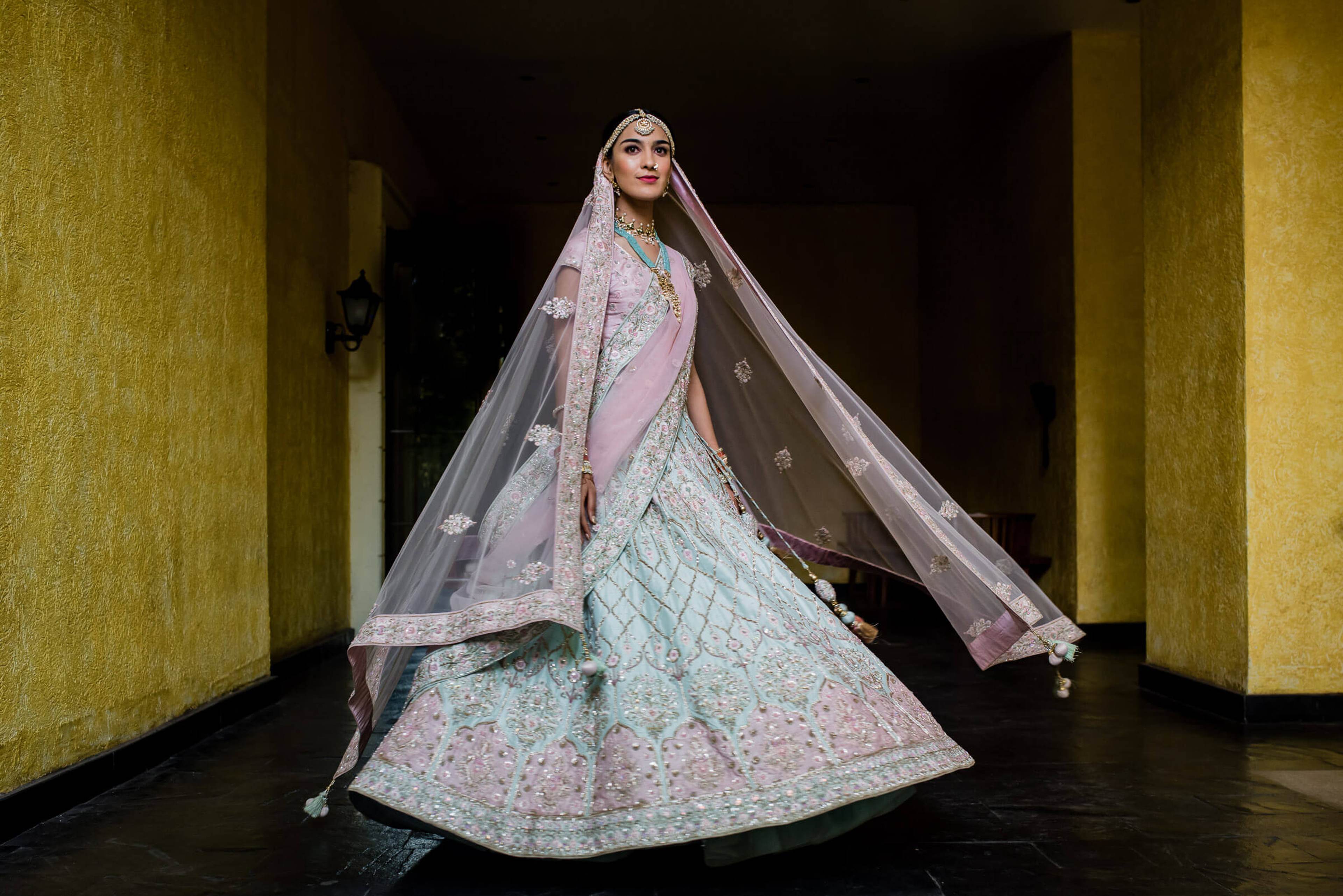 Shreya in ornate pink and white lehenga with flowing veil, standing in golden-walled corridor at Mahabaleshwar