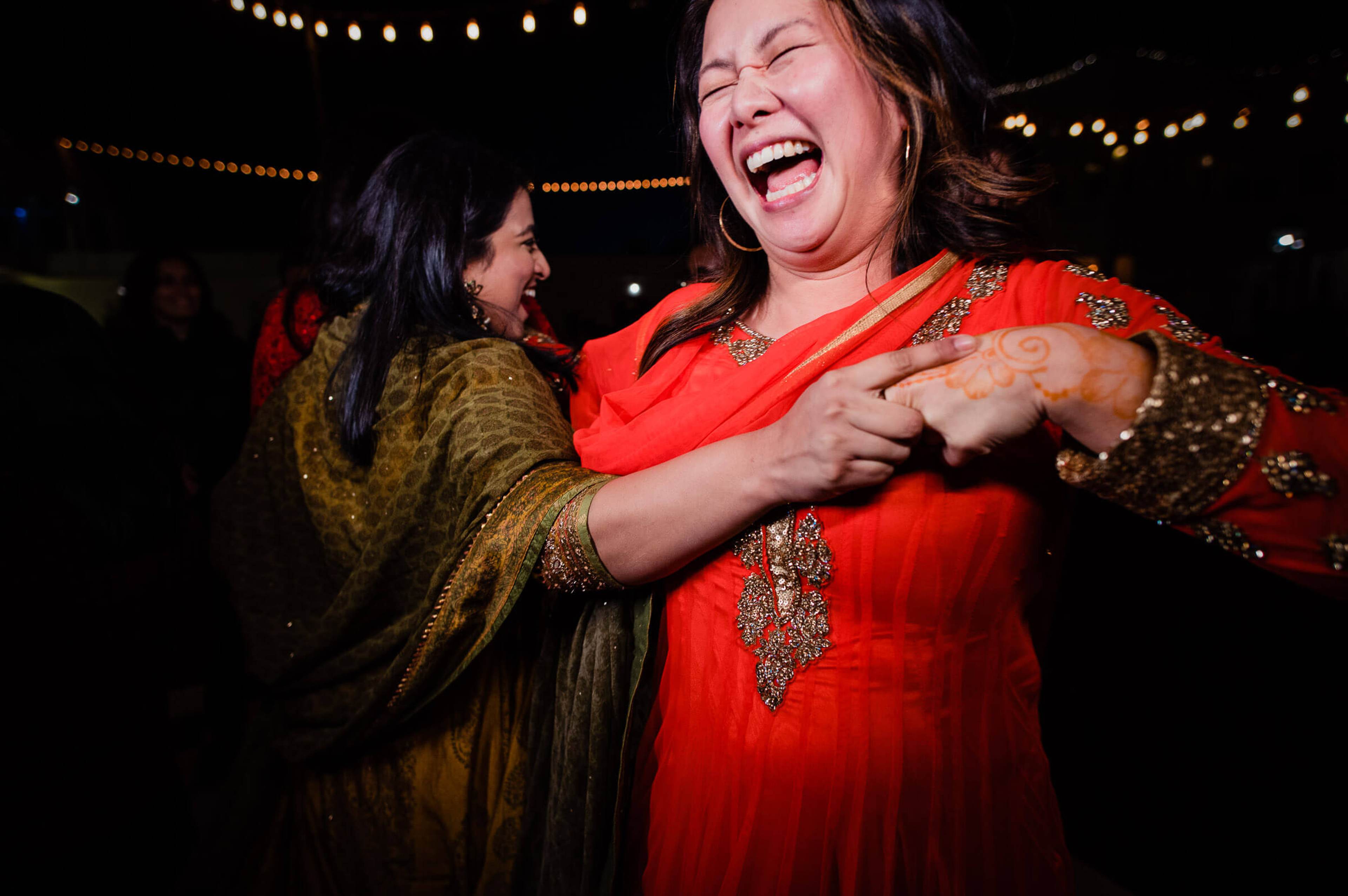 Maitrayee laughs joyfully in red embellished attire while dancing under festive lights in Rajasthan