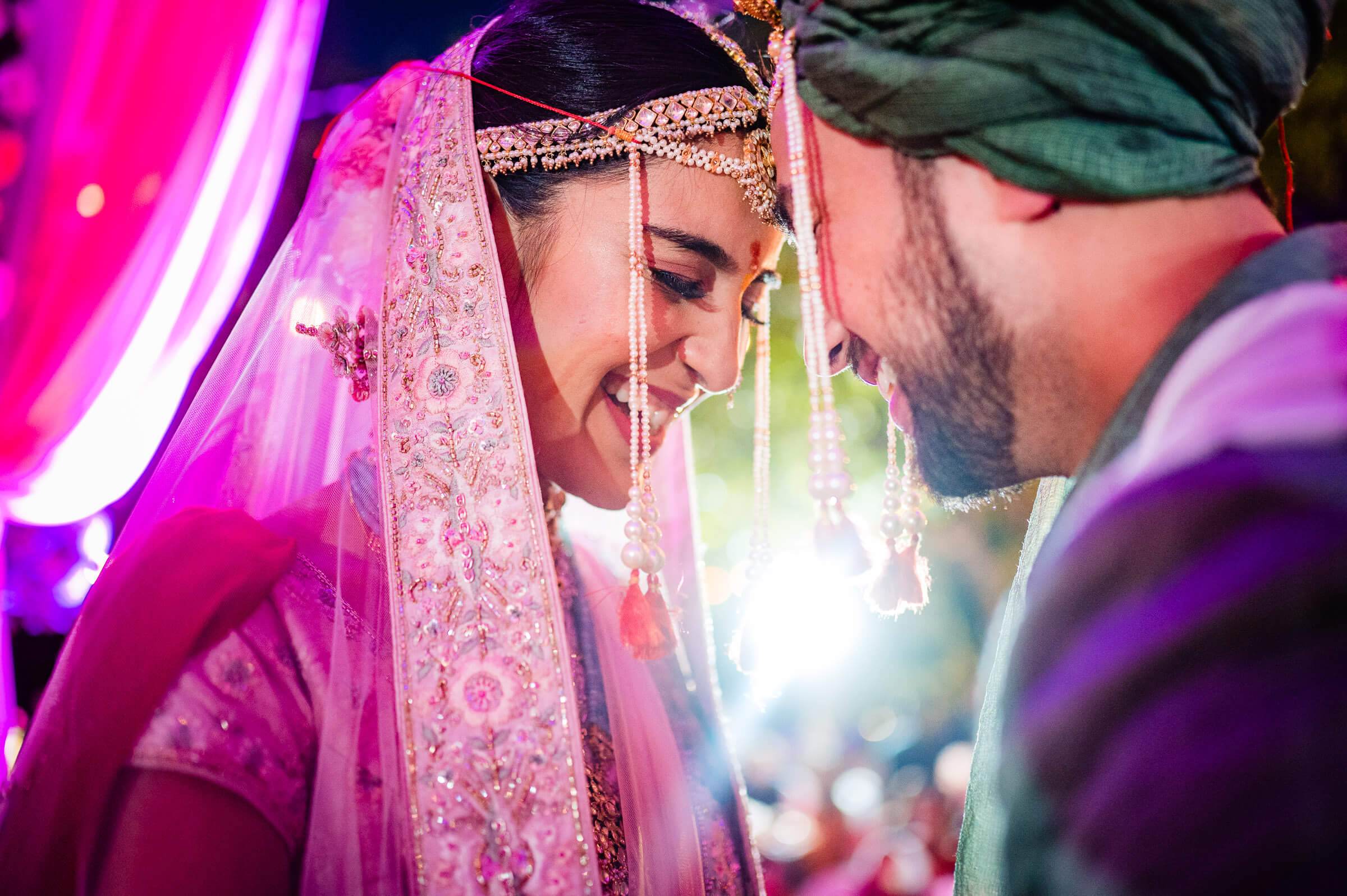 Shreya in ornate pink veil and gold jewelry gazes at Yash under vibrant magenta lighting at Mahabaleshwar