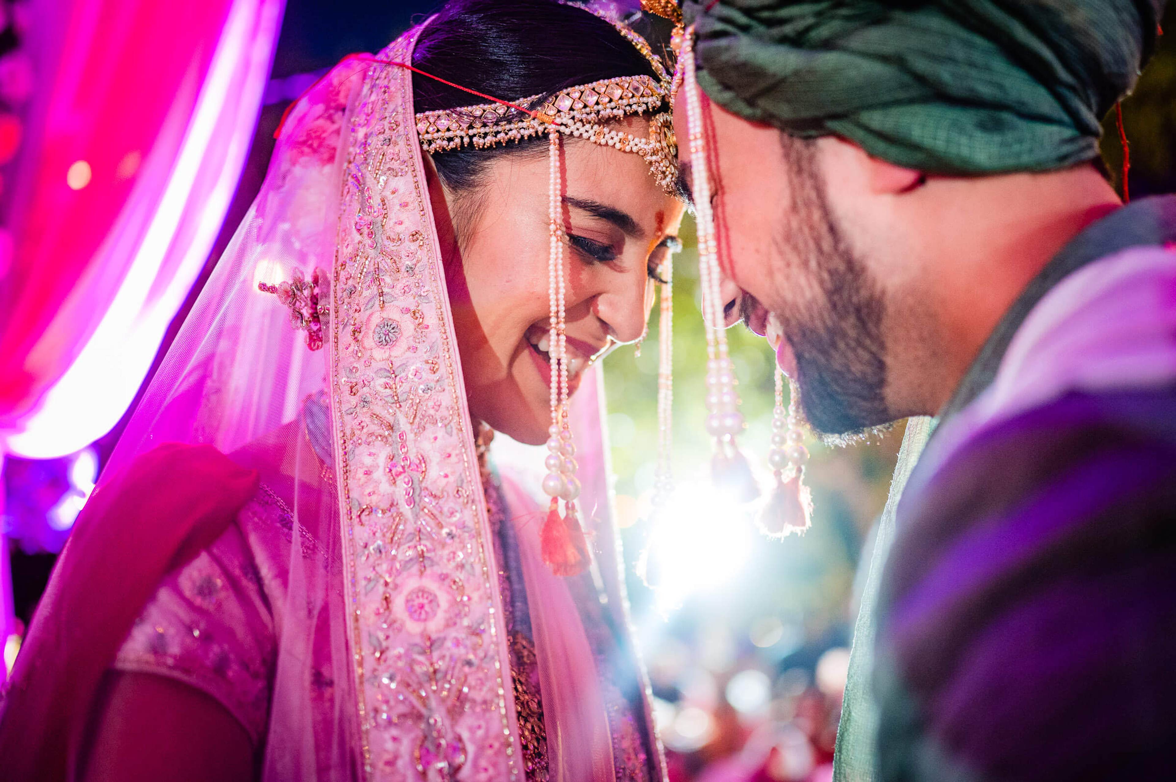 Shreya in ornate pink veil and gold jewelry gazes at Yash under vibrant magenta lighting at Mahabaleshwar