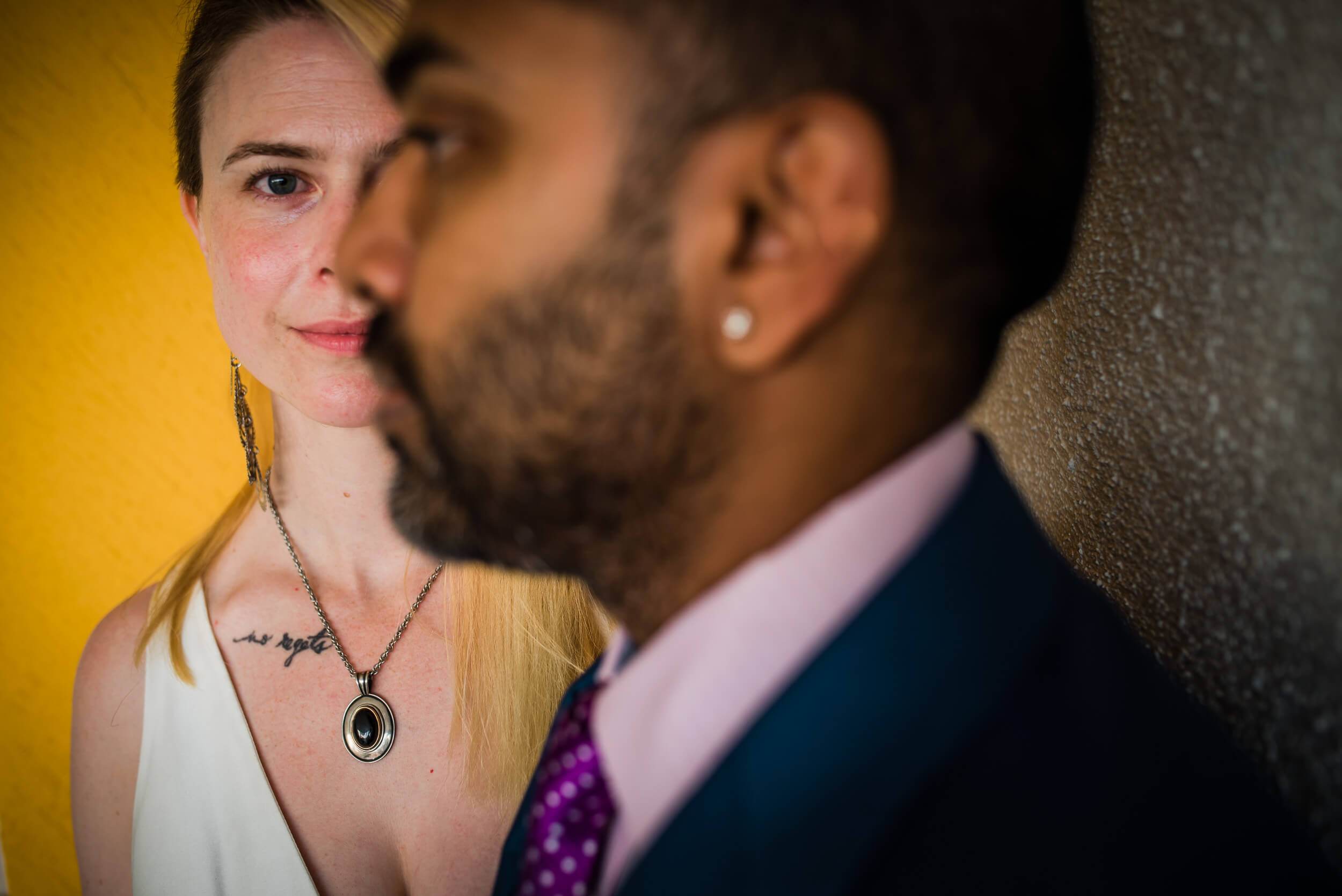 Sarah and Ravin face each other against warm yellow and gray backdrop lighting