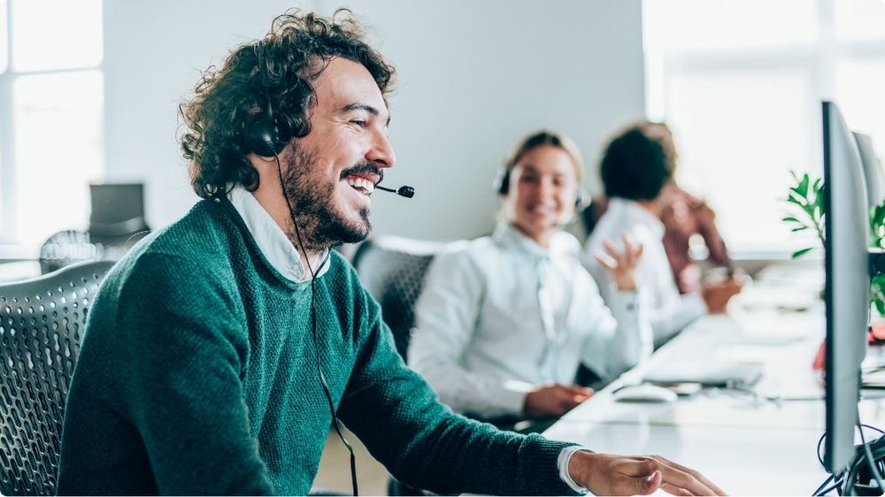 Smiling customer service agent wearing a headset in a modern office