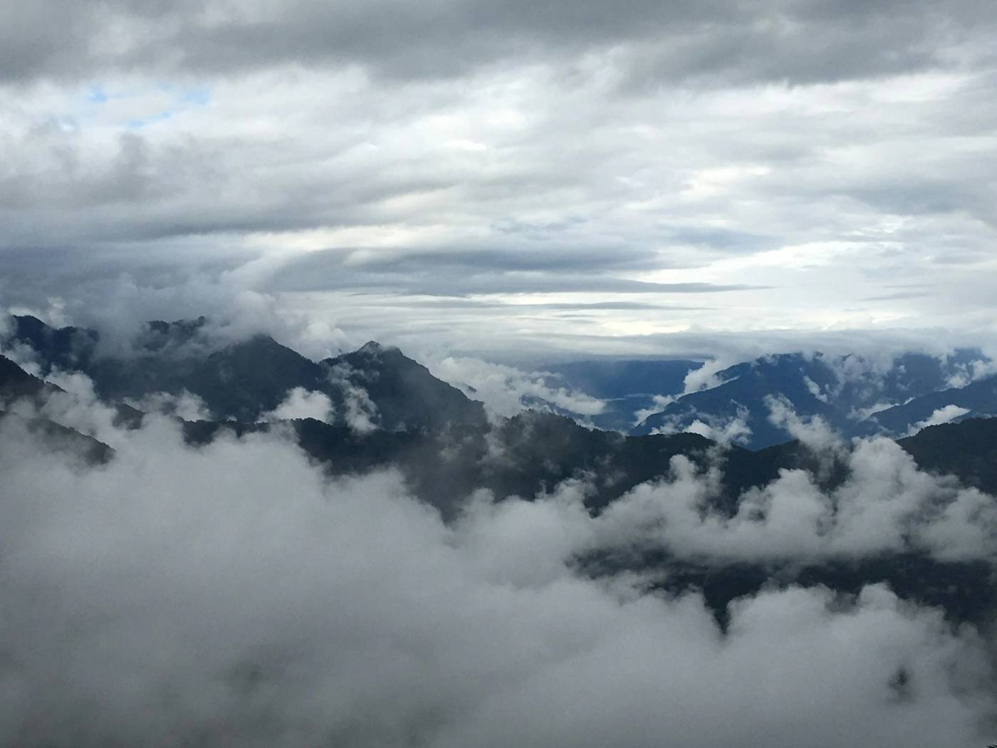 Cloud pooling between dark forested mountain ridges on a grey day