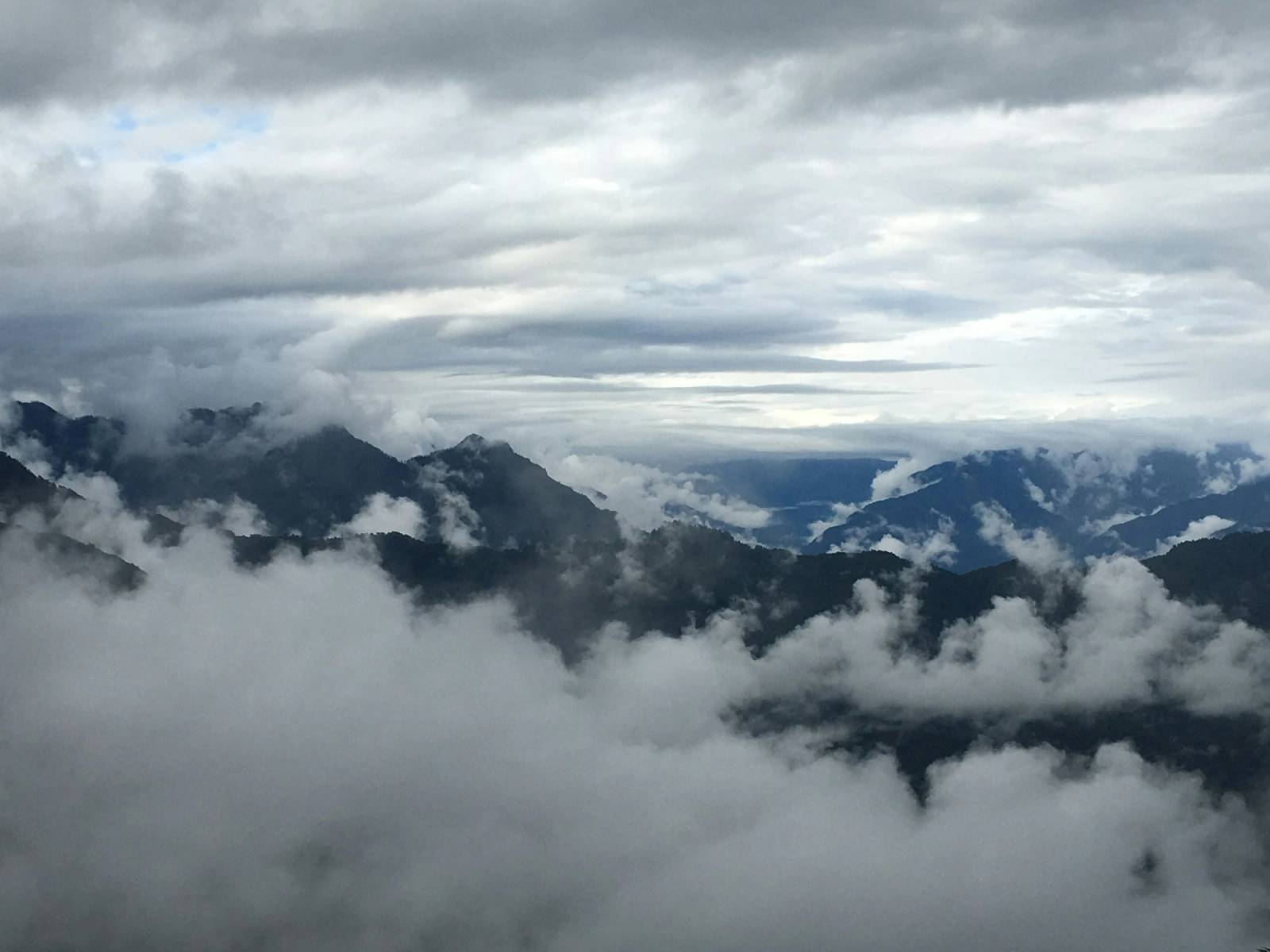 Cloud pooling between dark forested mountain ridges on a grey day