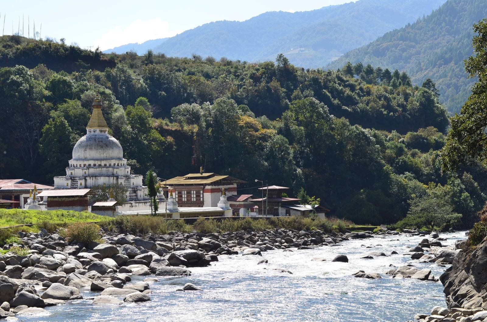 Chorten Kora's white dome and gold spire beside a boulder-strewn river in Trashiyangtse