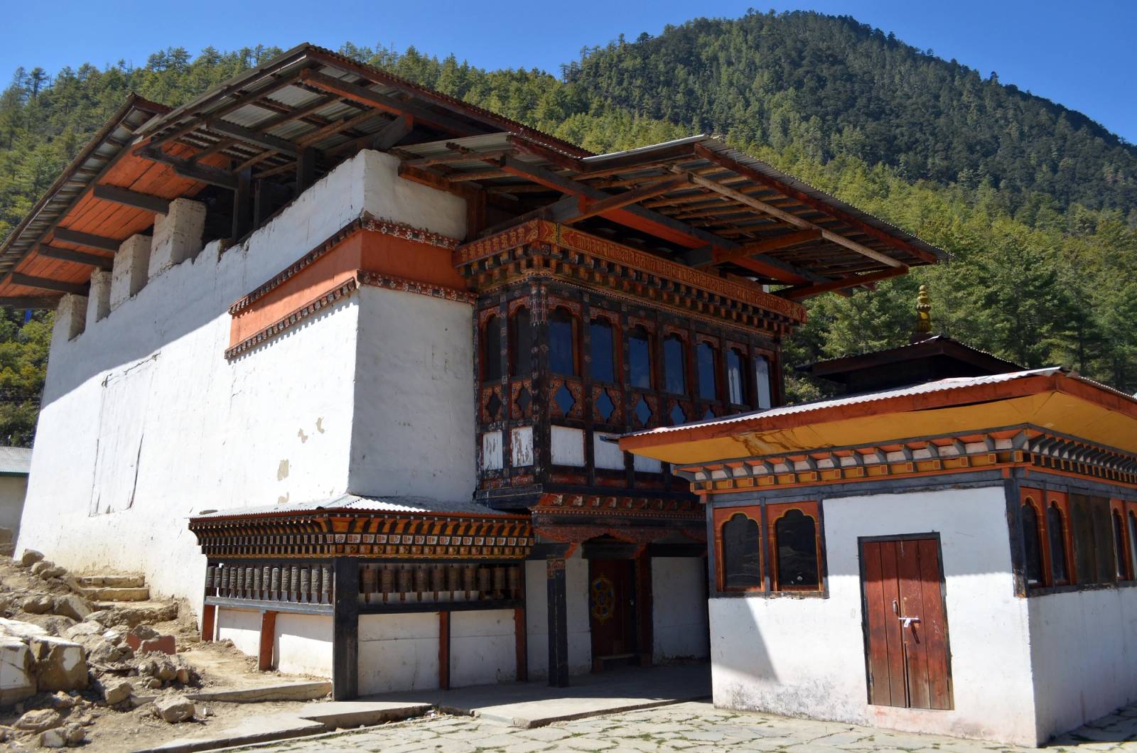 Lhakhang Karpo, the White Temple of Haa, with its prayer wheels below forested hills