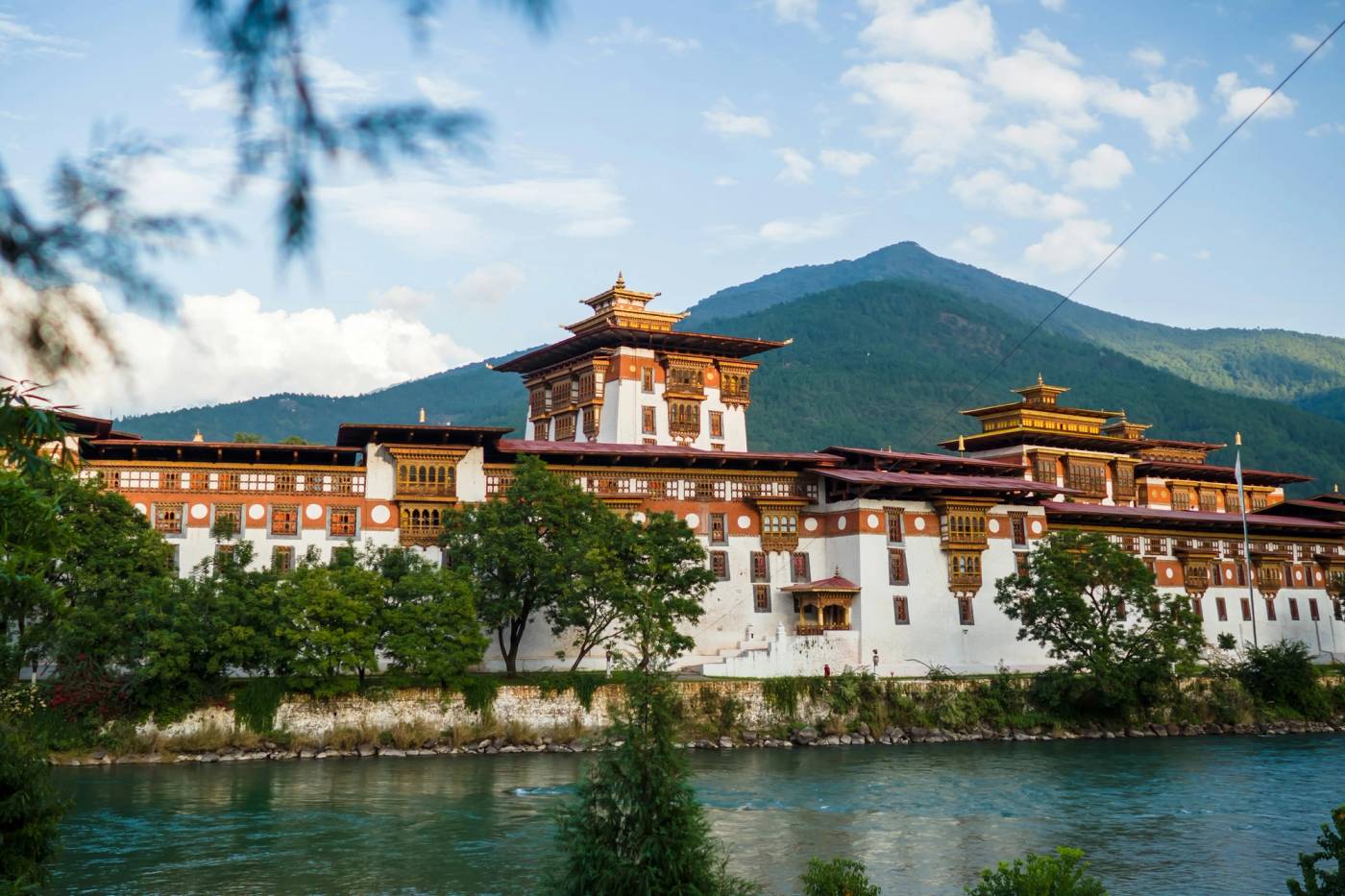 Punakha Dzong's white walls and golden towers above a blue-green river, a mountain behind