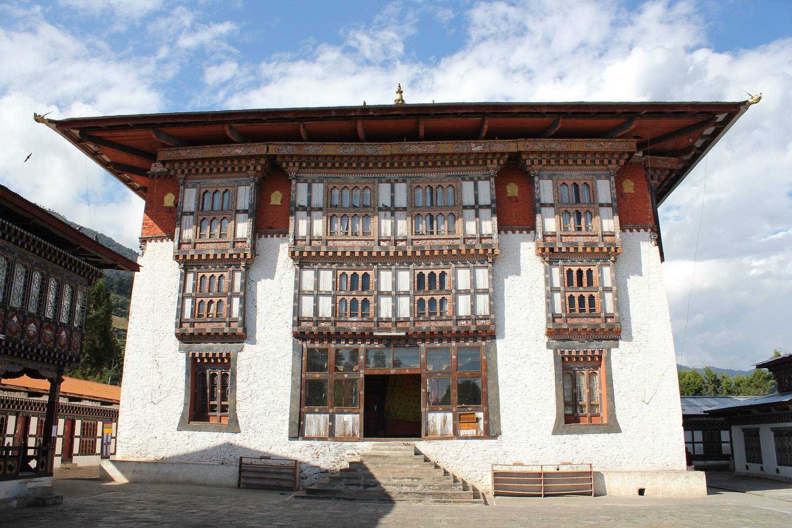 The whitewashed main temple of Drametse Lhakhang with its carved wooden windows, seen across the courtyard