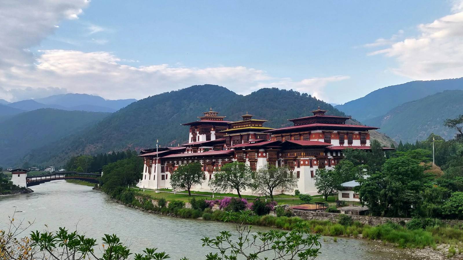 Punakha Dzong on the riverbank, with its covered wooden bridge and green hills behind