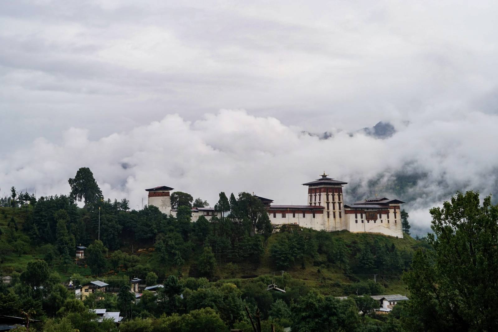 Jakar Dzong on its hillside above Jakar town, with low cloud over the ridge behind