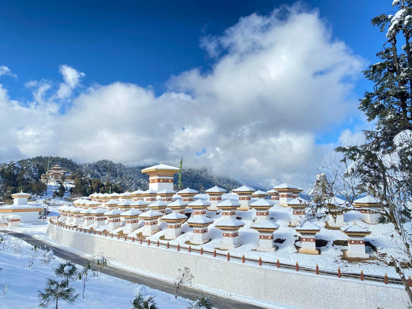 The 108 chortens of Dochu La under fresh snow, with blue sky and cloud