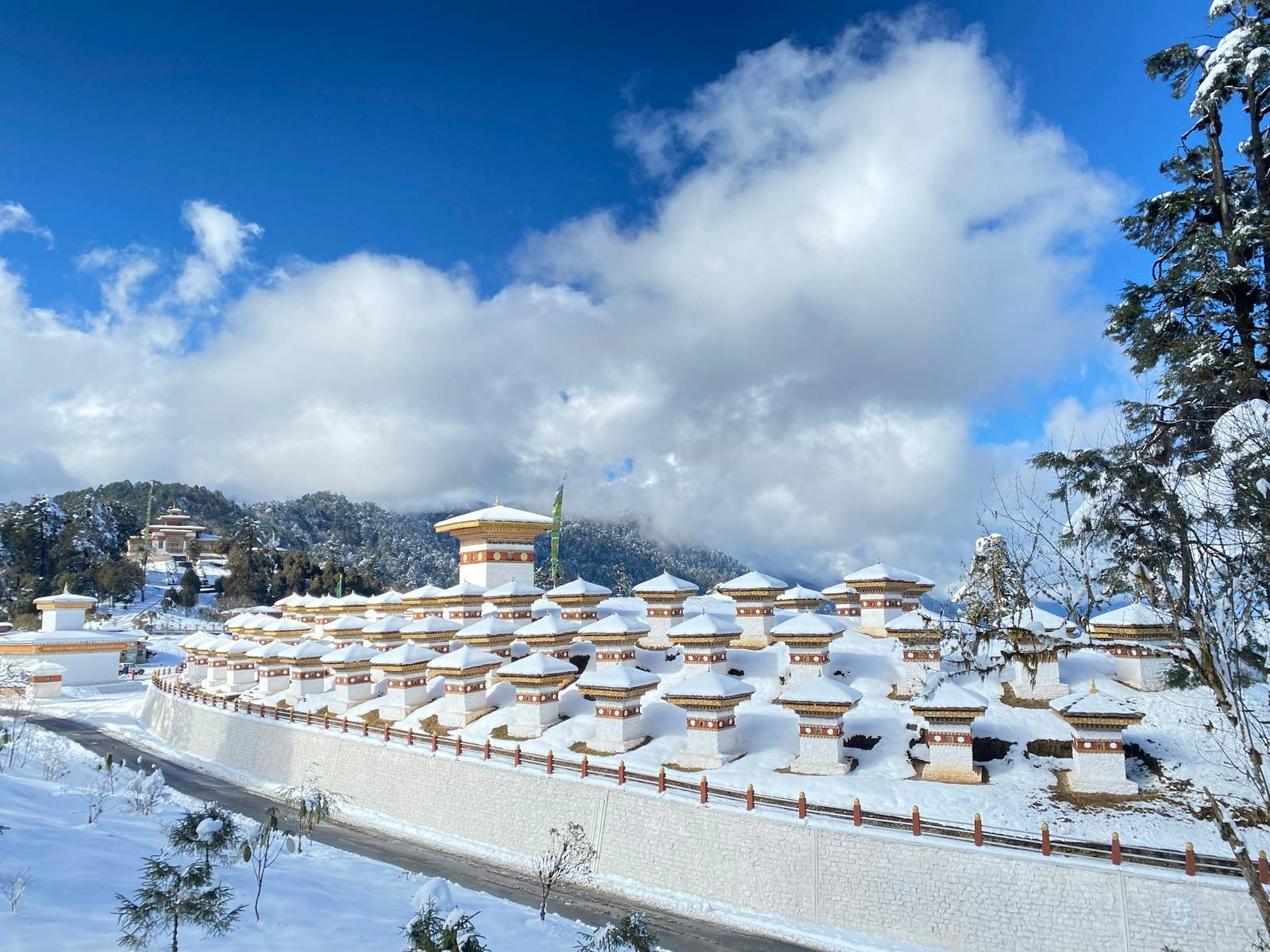 The 108 chortens of Dochu La under fresh snow, with blue sky and cloud