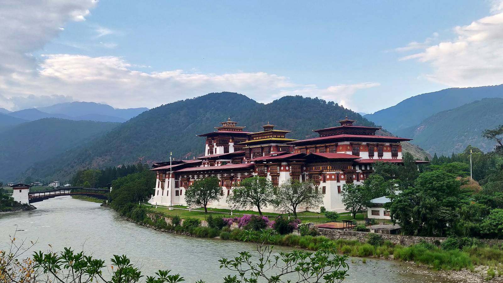 Punakha Dzong on the riverbank, with its covered wooden bridge and green hills behind