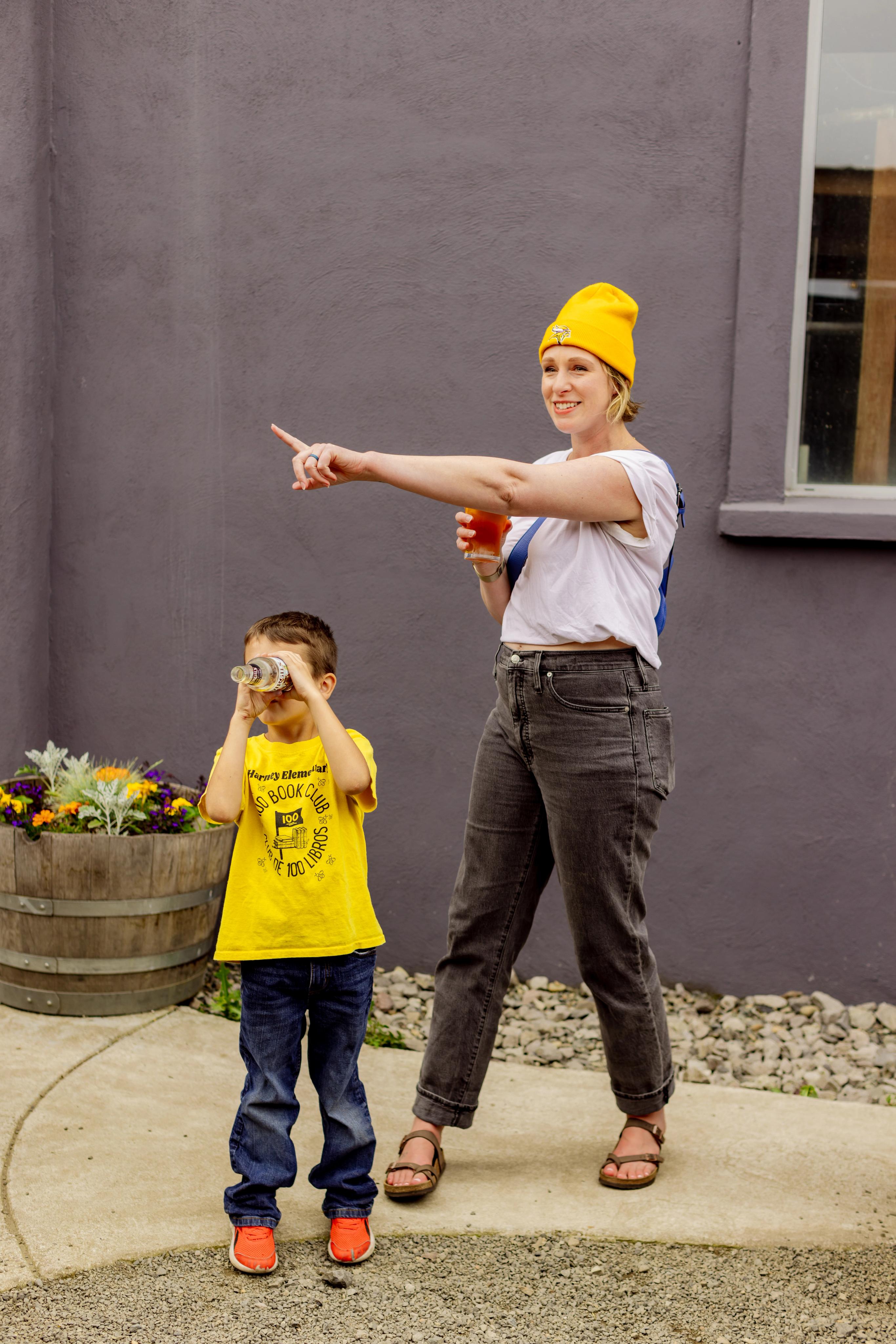 Woman pointing in a direction and child looking through a telescope