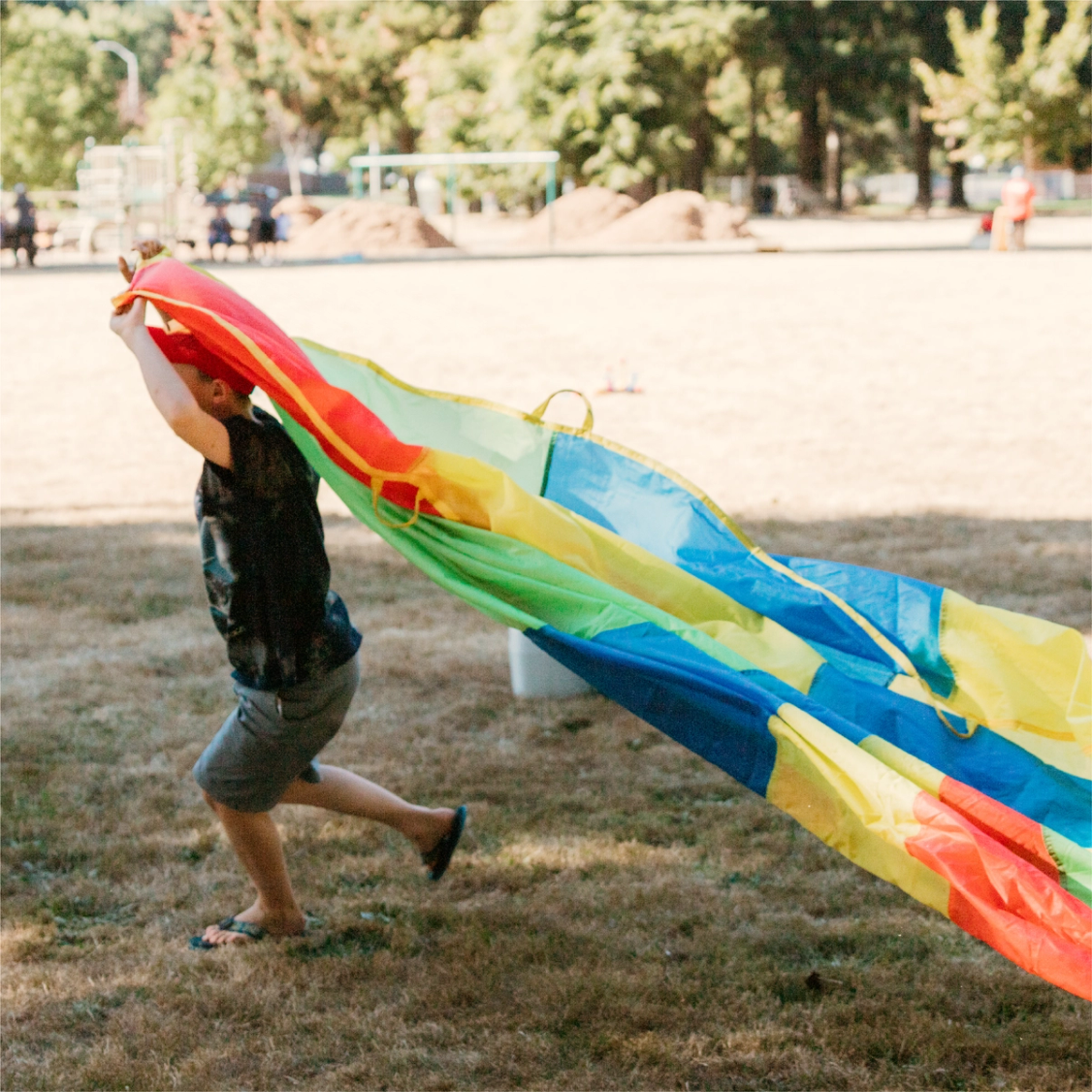 Child running while pulling play parachute