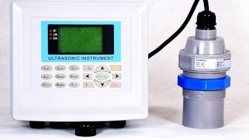 Ultrasonic level sensor mounted above a V-notch weir measuring water head in an open concrete channel for level-to-flow conversion
