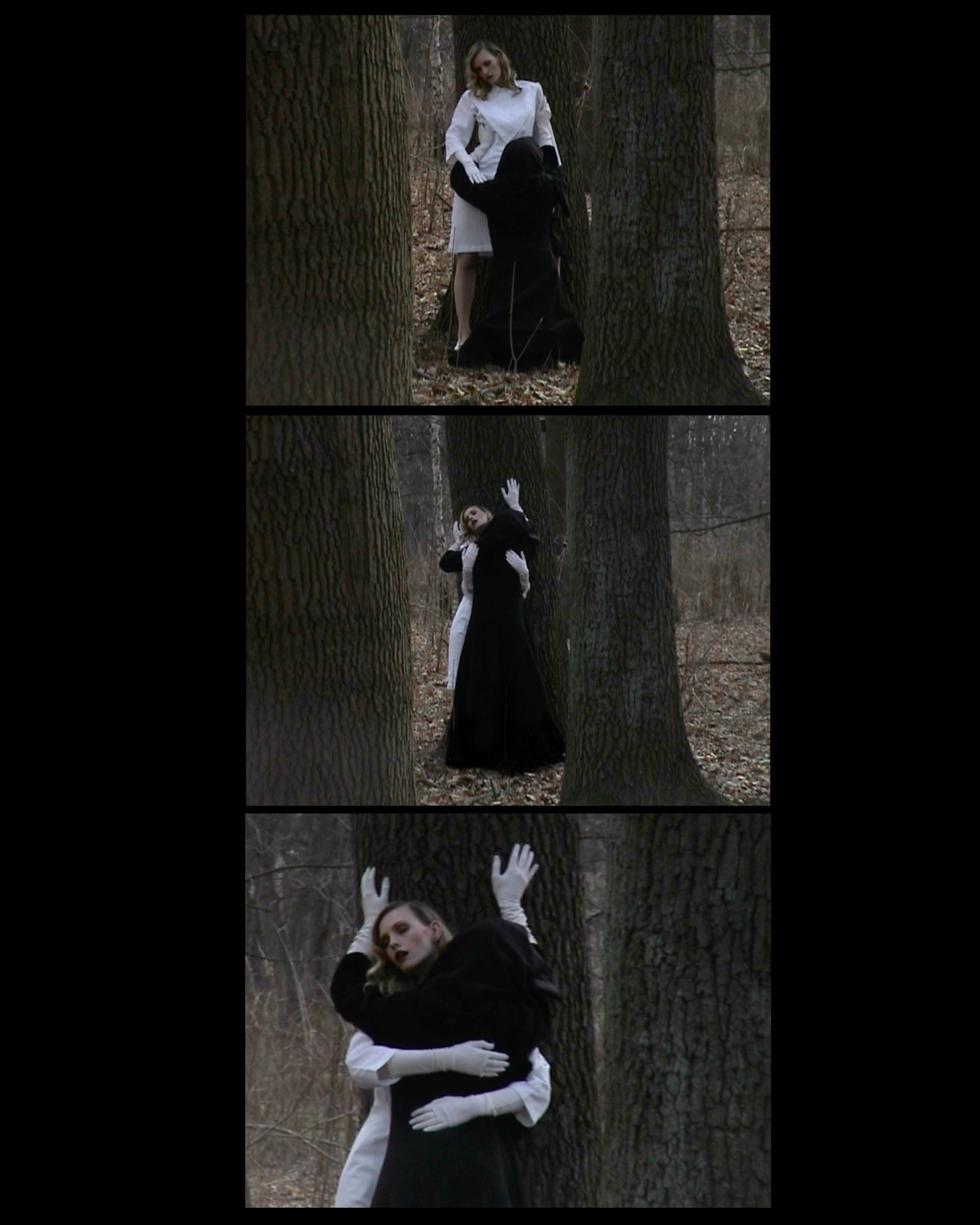 Alt Text: Two figures stand between tall trees — one in white, the other cloaked in black — locked in a tense, ritual-like embrace. SEO Caption: King Kong Magazine editorial — forest tableau of duality in black-and-white styling, photographed by Josephine Meng.