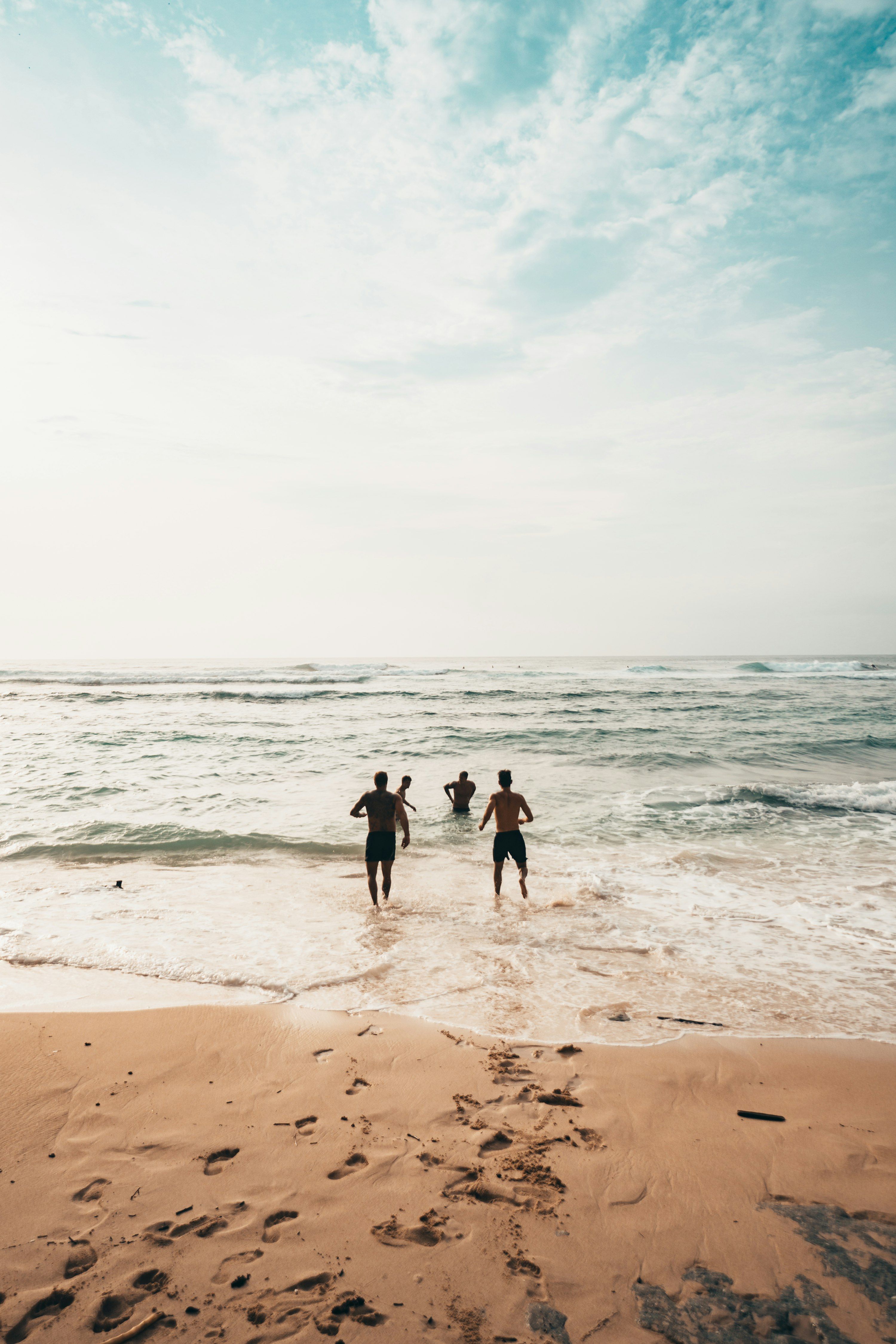Vennegruppe løber ned mod en solbeskinnet strand og havet