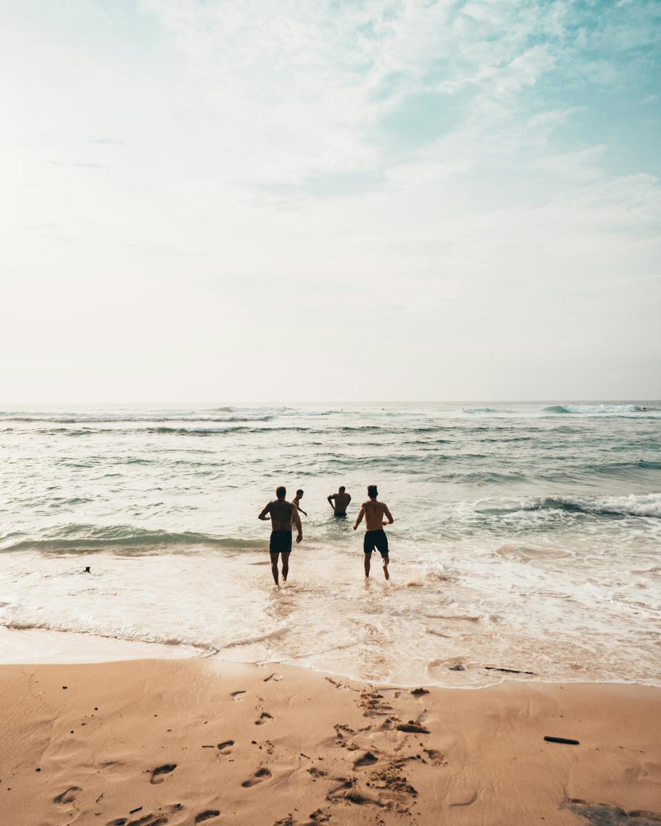 Vennegruppe løber ned mod en solbeskinnet strand og havet
